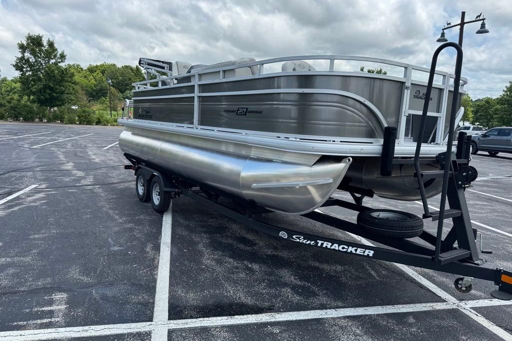 2026 Sun Tracker Fishin' Barge 20 DLX pontoon boat on trailer in parking lot.