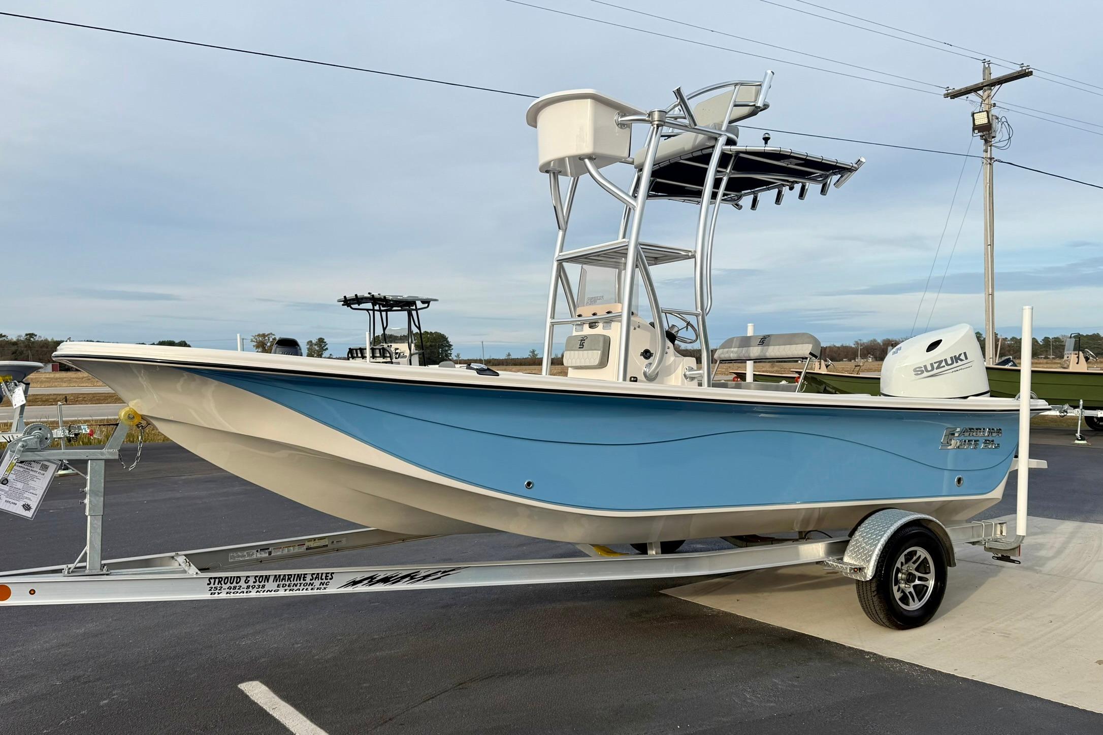 2025 Carolina Skiff 21 LS boat on trailer, featuring a blue hull and Suzuki outboard motor.