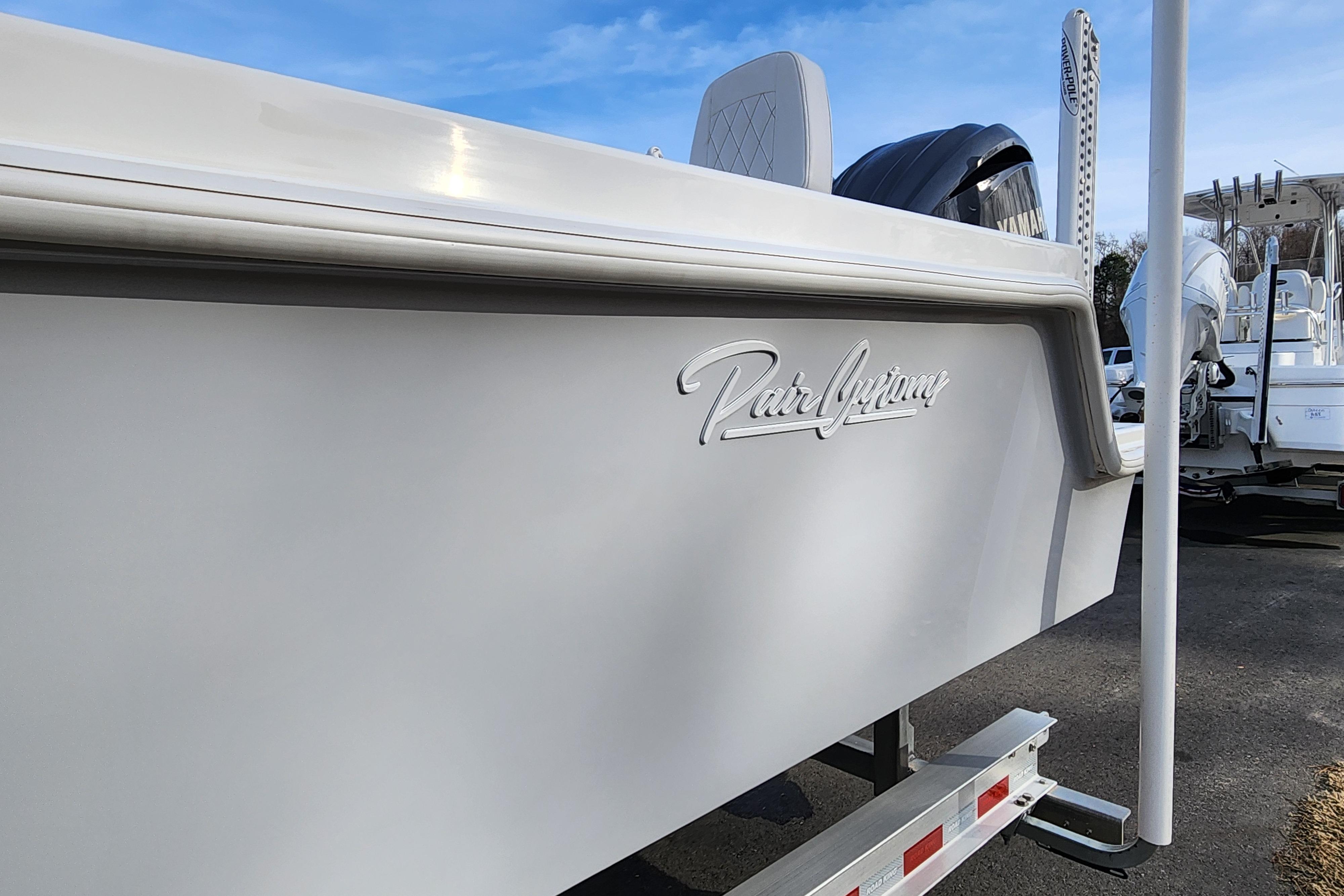 2024 Pair Customs 27 CC boat side view with logo, parked on a trailer.