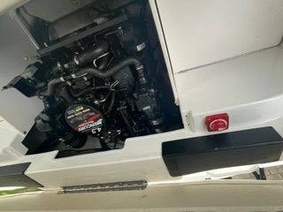 An open engine compartment of a boat showing the engine and hoses.