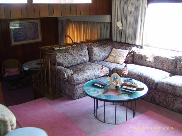 1980 Pluckebaum Baymaster interior with vintage decor, plush seating, and a round glass coffee table.