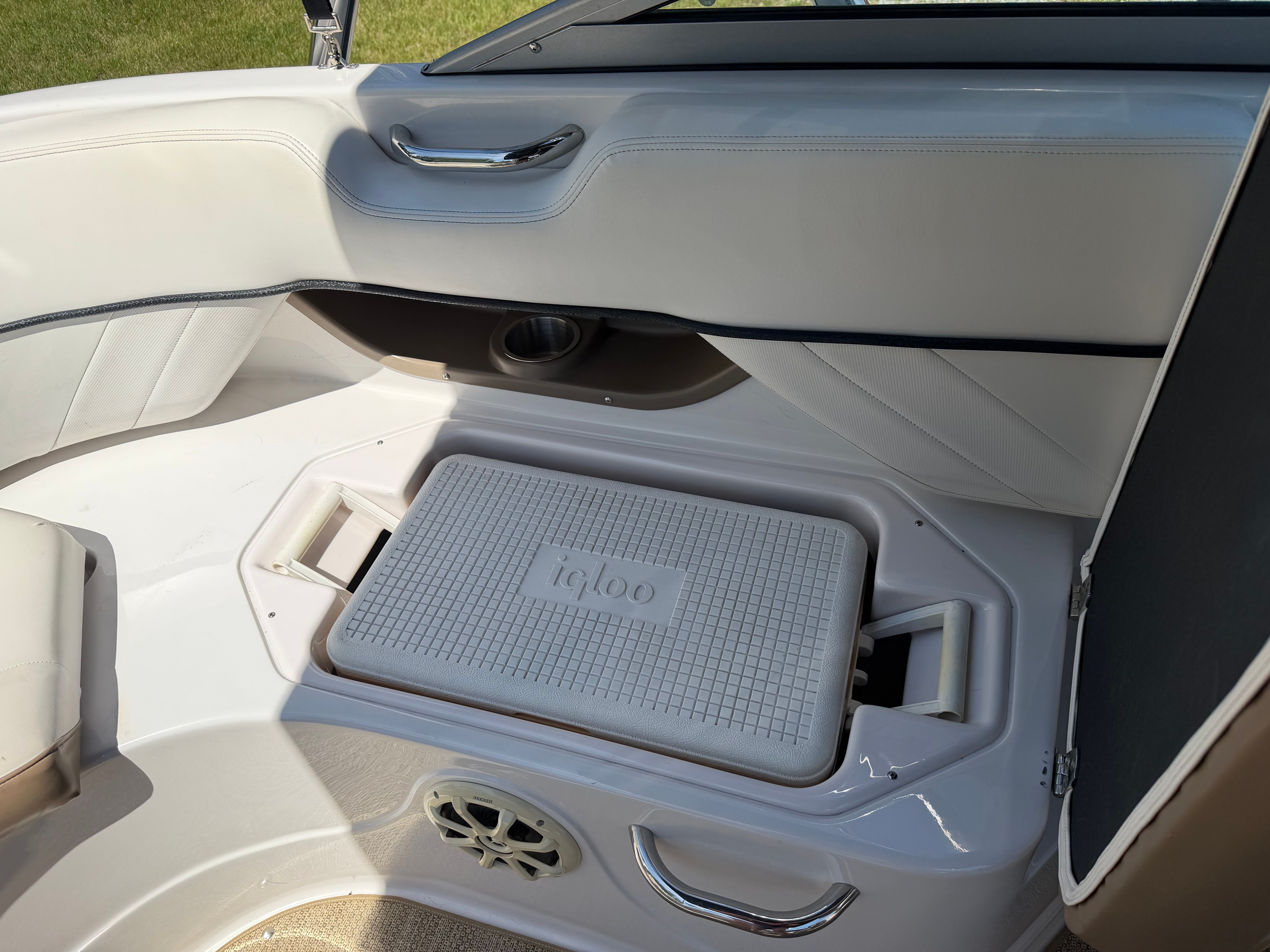 Boat interior with white seating and built-in cooler.