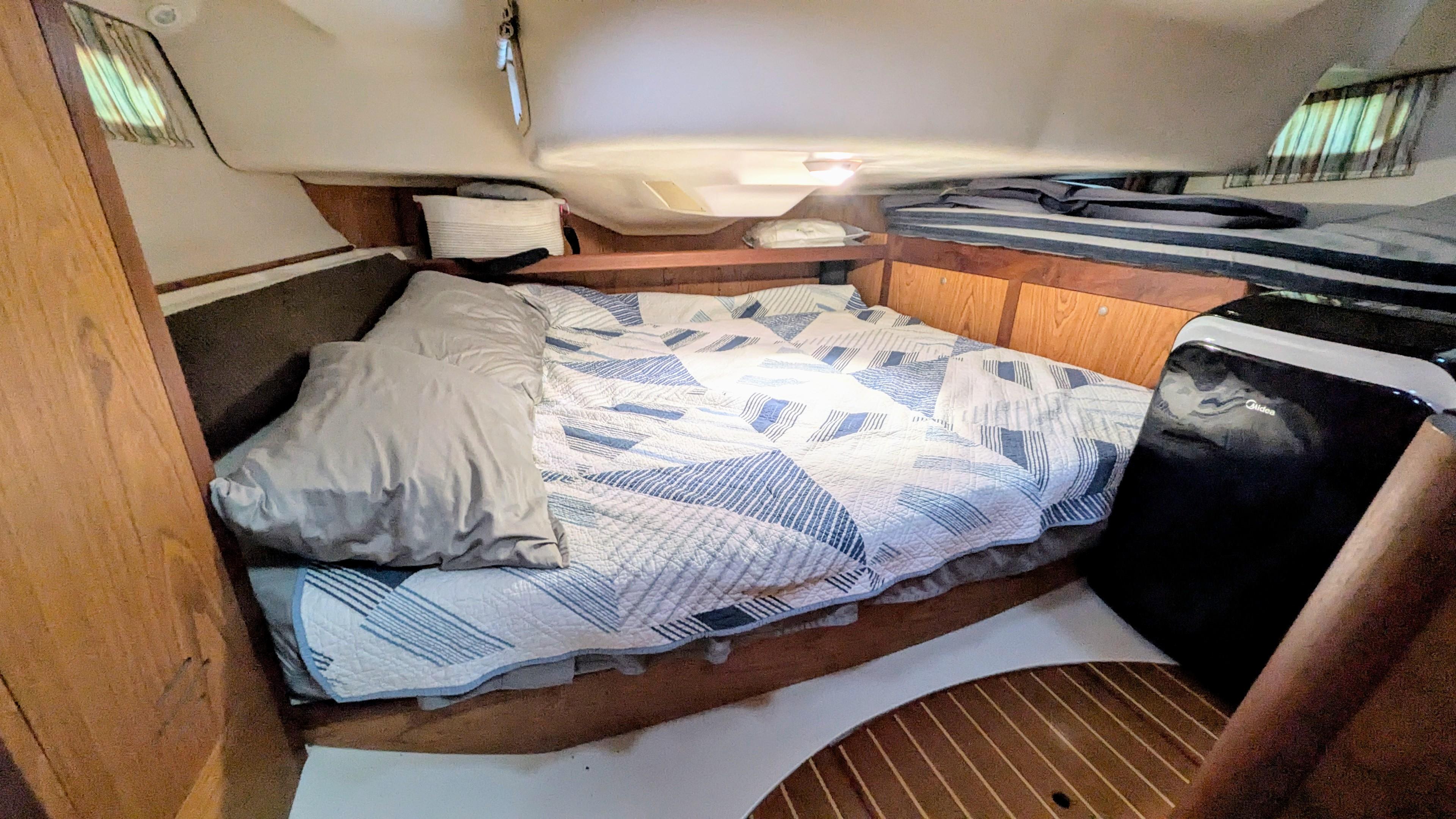 Cozy cabin interior of 2001 Hunter 380 sailboat with bed and compact fridge.