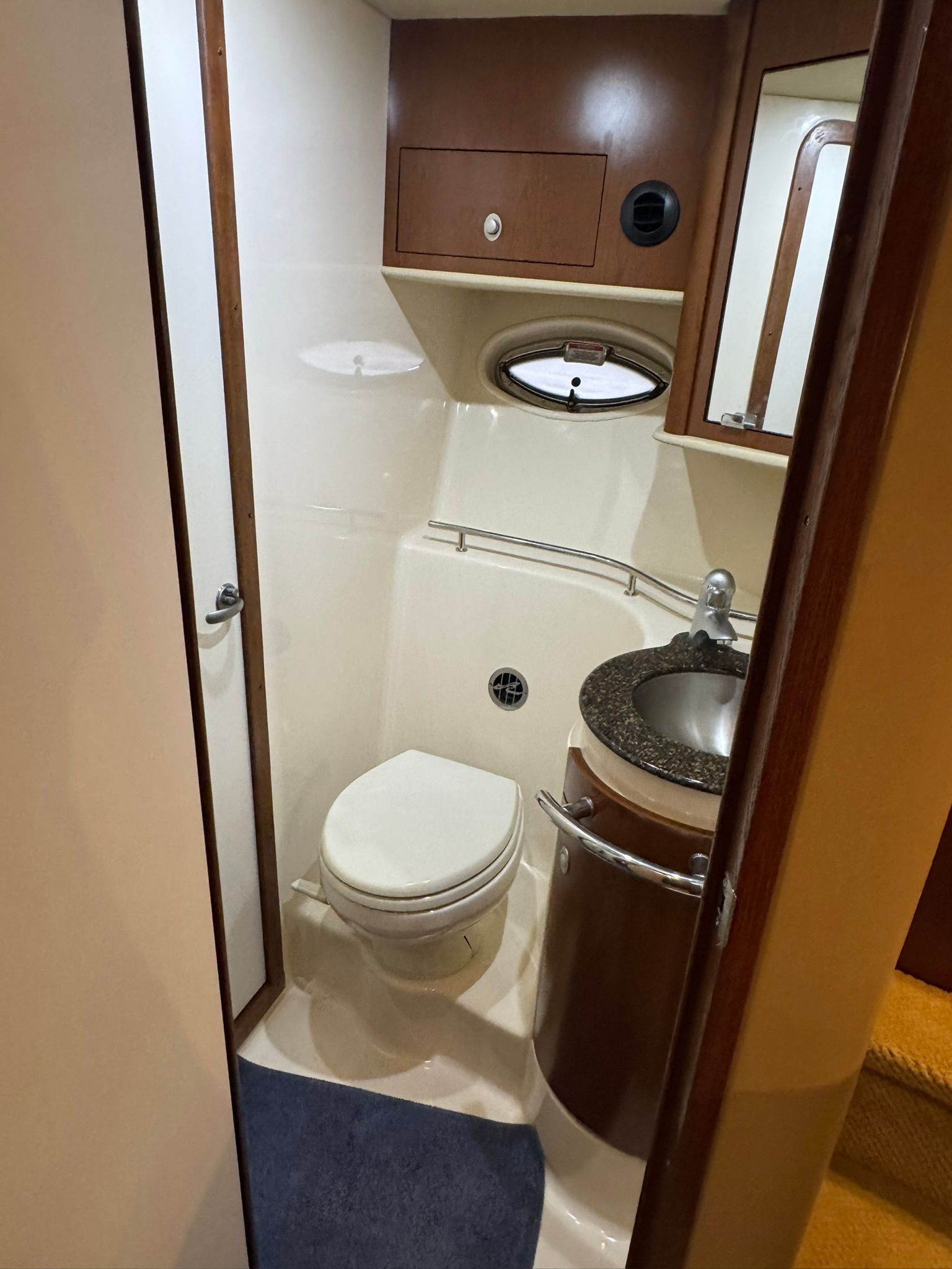 The image shows a boat bathroom with a toilet, sink, and mirror.
