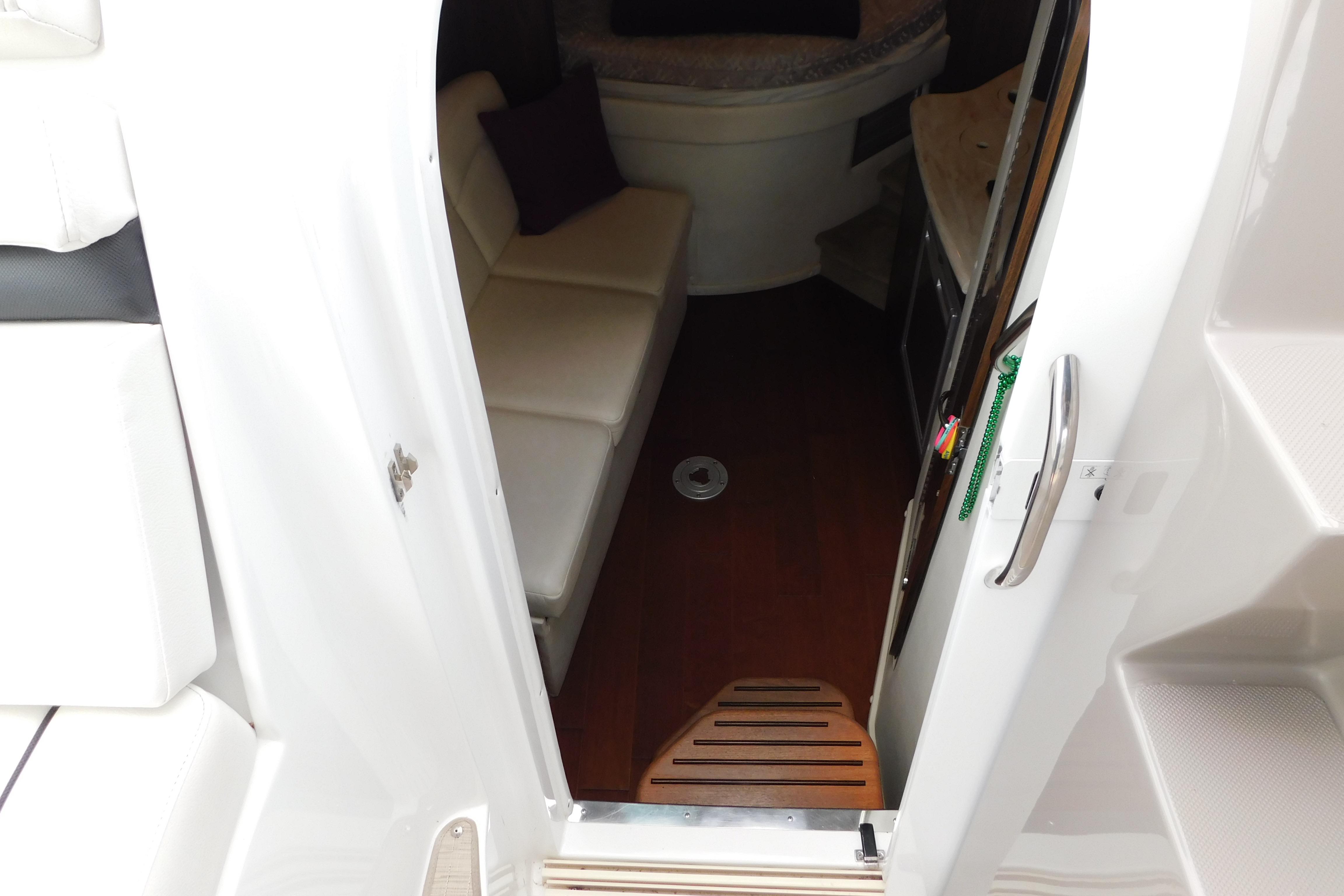 Interior view of 2017 Rinker EX 320 boat cabin with seating and wood flooring.