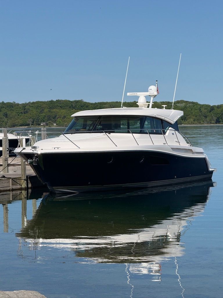 A 2017 Tiara Yachts C44 Coupe is docked calmly in clear water.