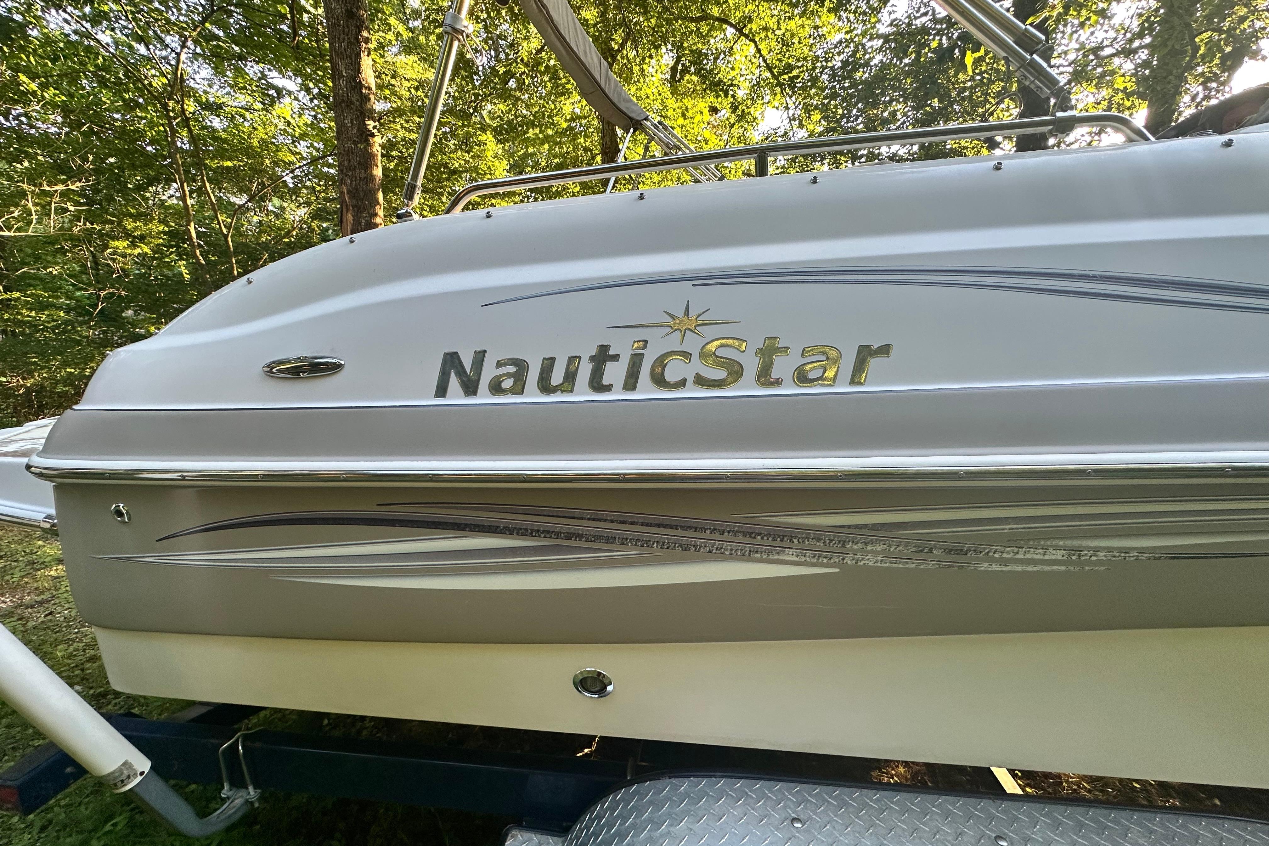 2008 NauticStar 230 SL Sport Deck I/O boat in wooded setting.