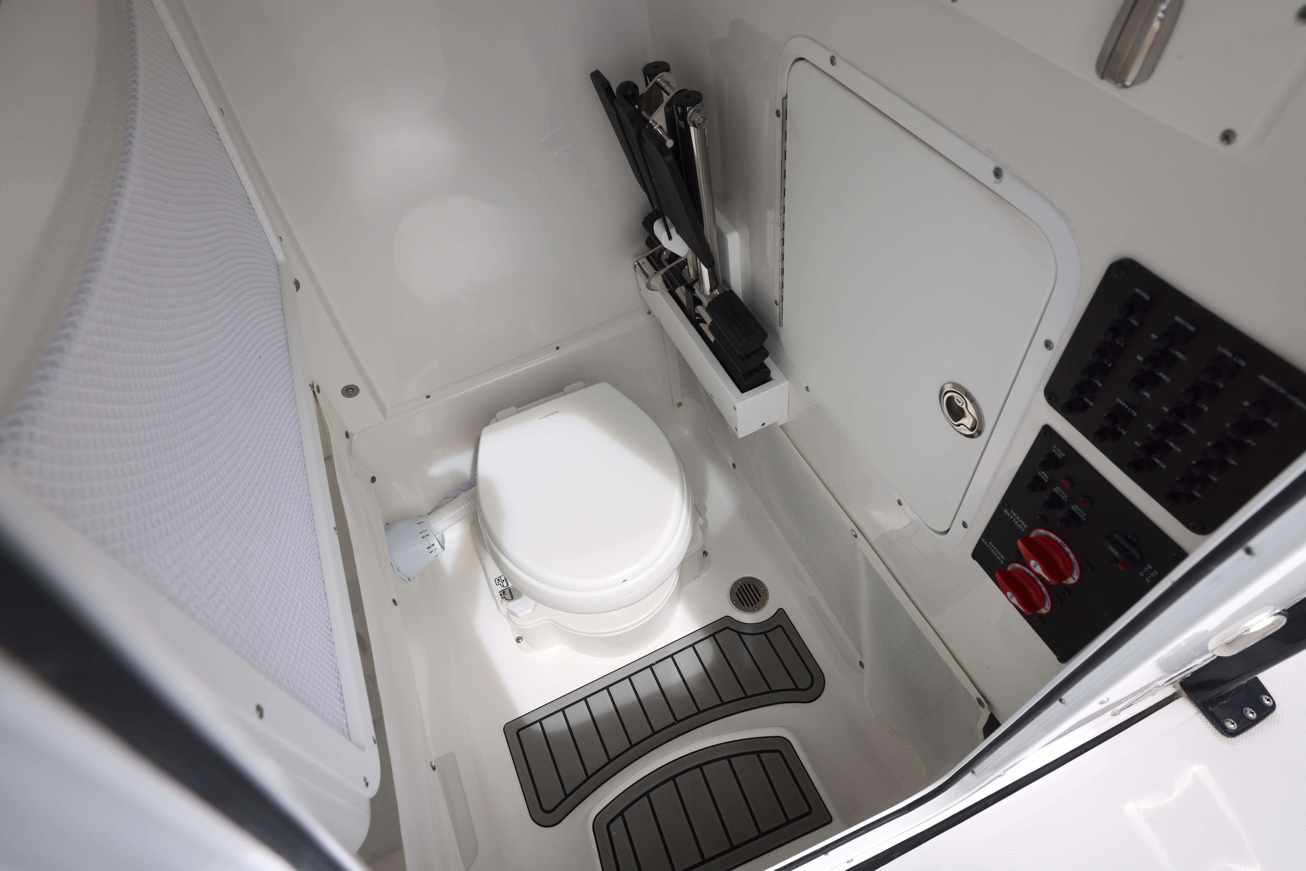 Interior of 2026 Sea Hunt Gamefish 25 boat, featuring a compact marine toilet.