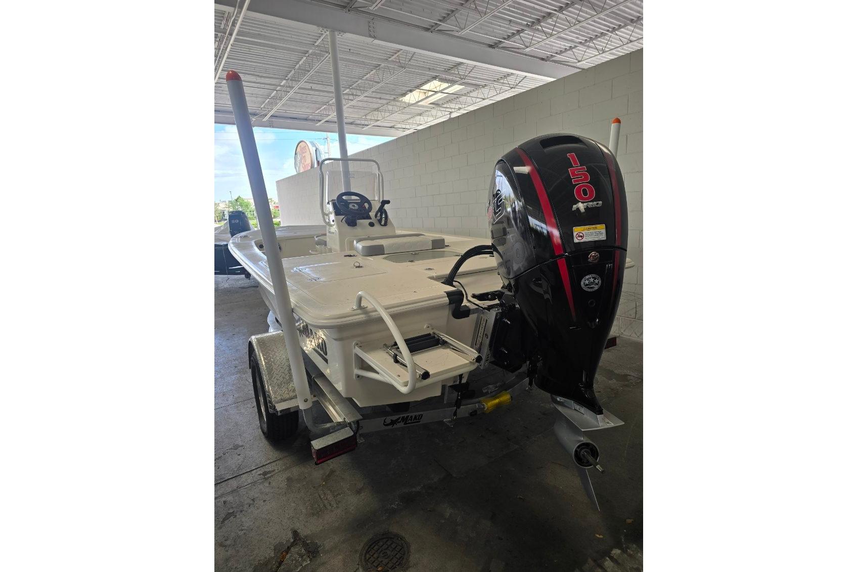 2026 Mako 18 Pro Skiff boat with powerful 150 HP outboard motor in a garage.
