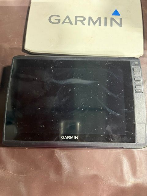 A Garmin navigation device on a brown surface, with a Garmin box beside it.