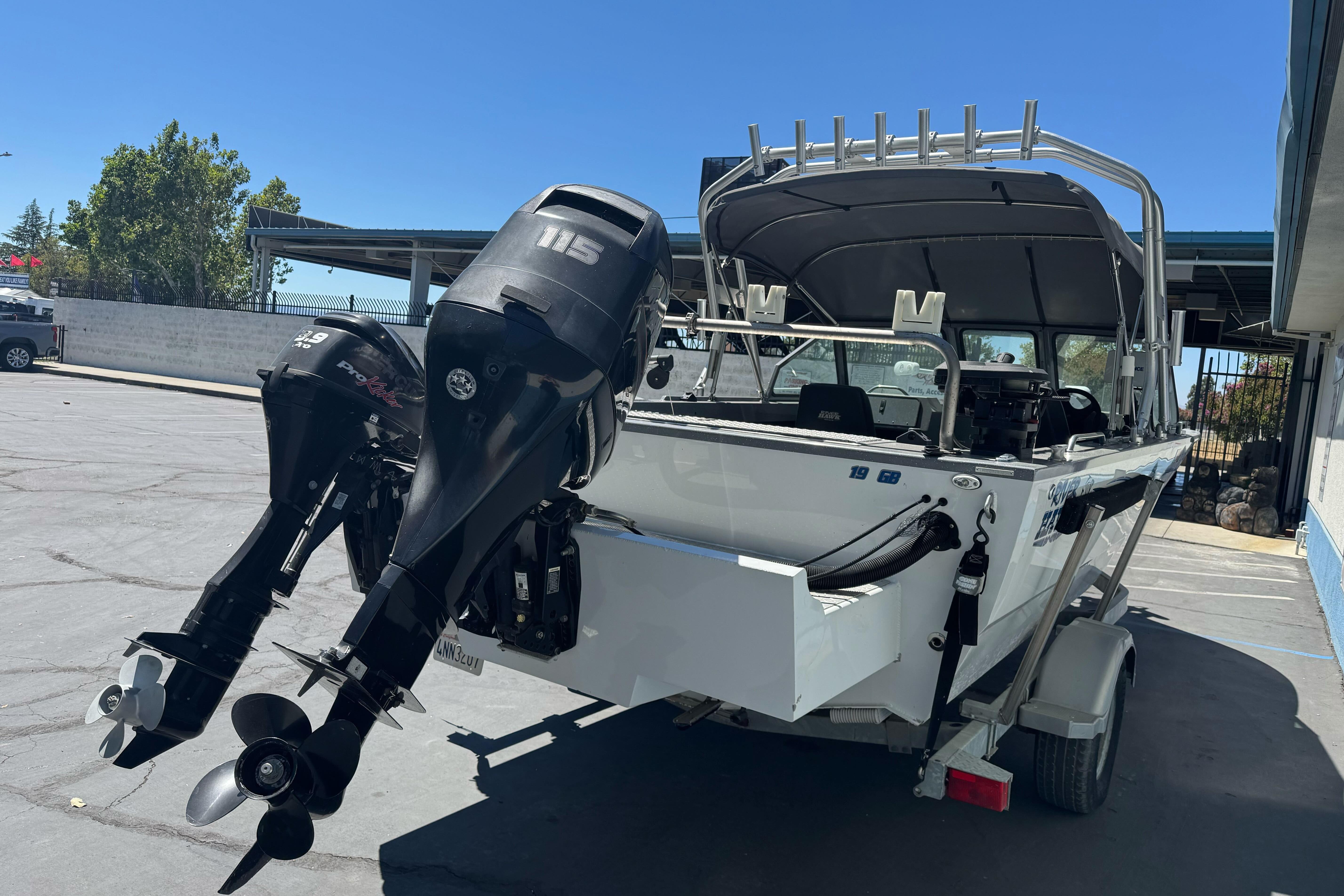 2014 River Hawk 19 GB boat with dual outboard motors in a parking lot.