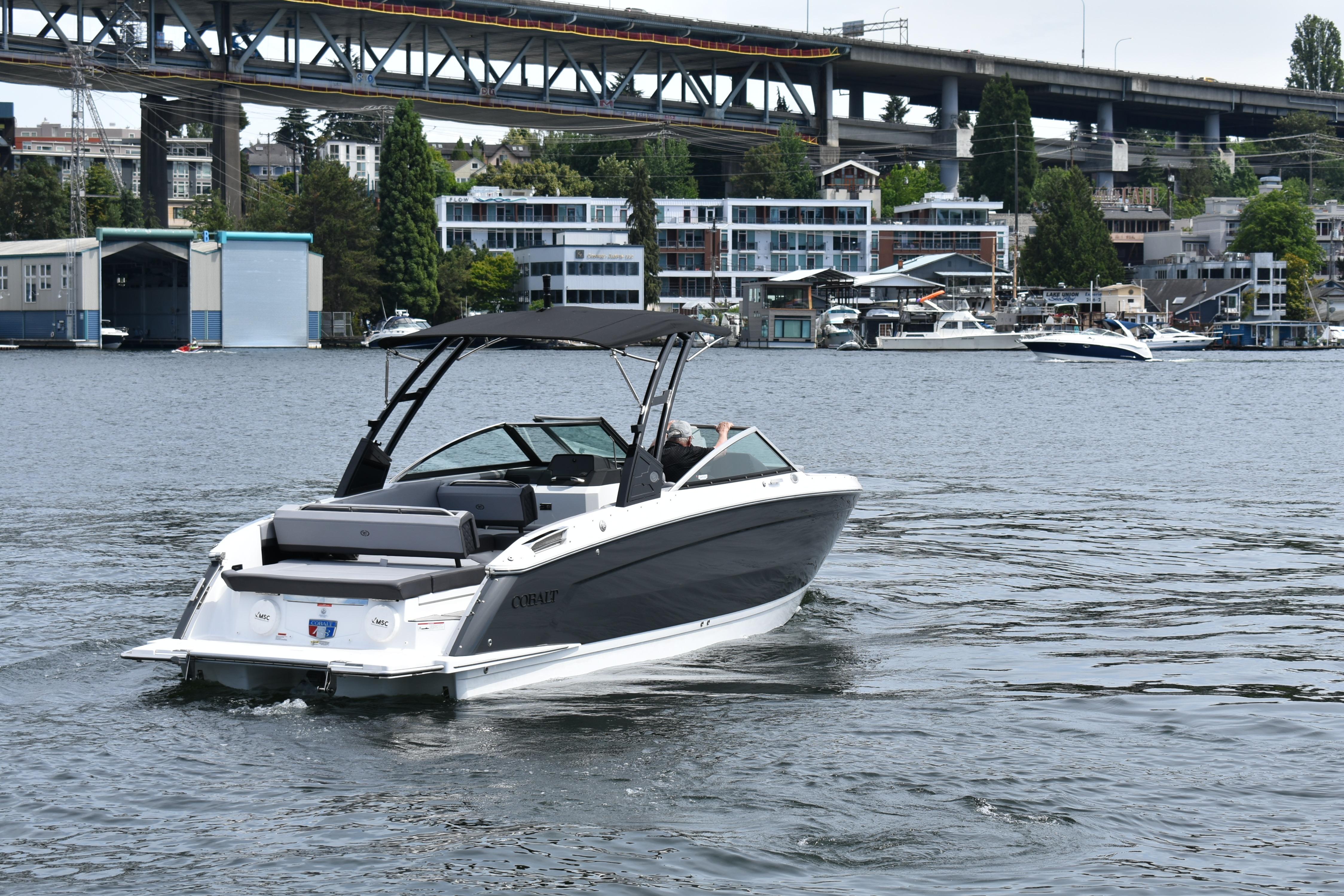 2023 Cobalt R8 boat cruising on a scenic urban waterway with bridge and buildings.