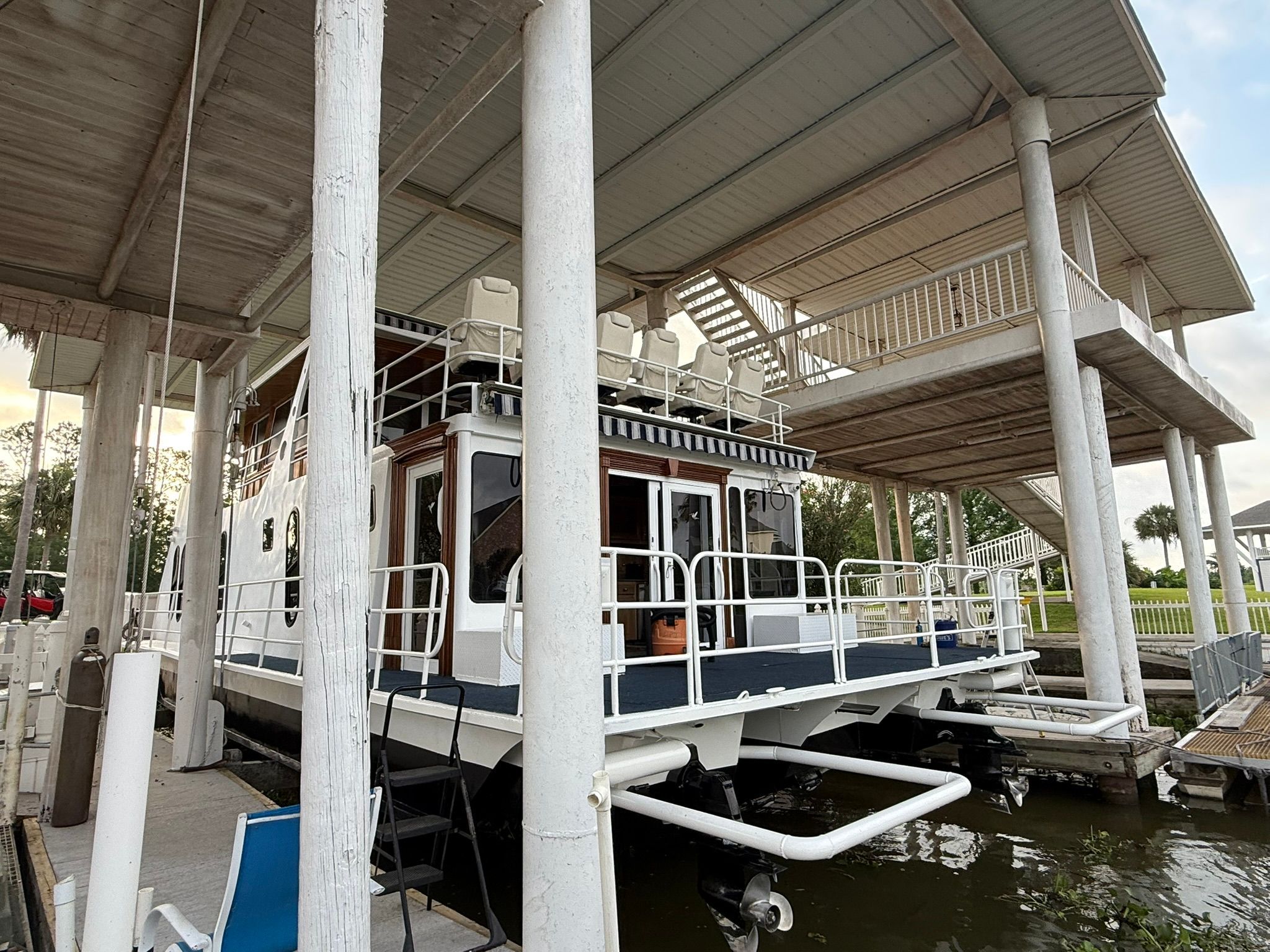 Houseboat under a covered dock with railings and stairs.
