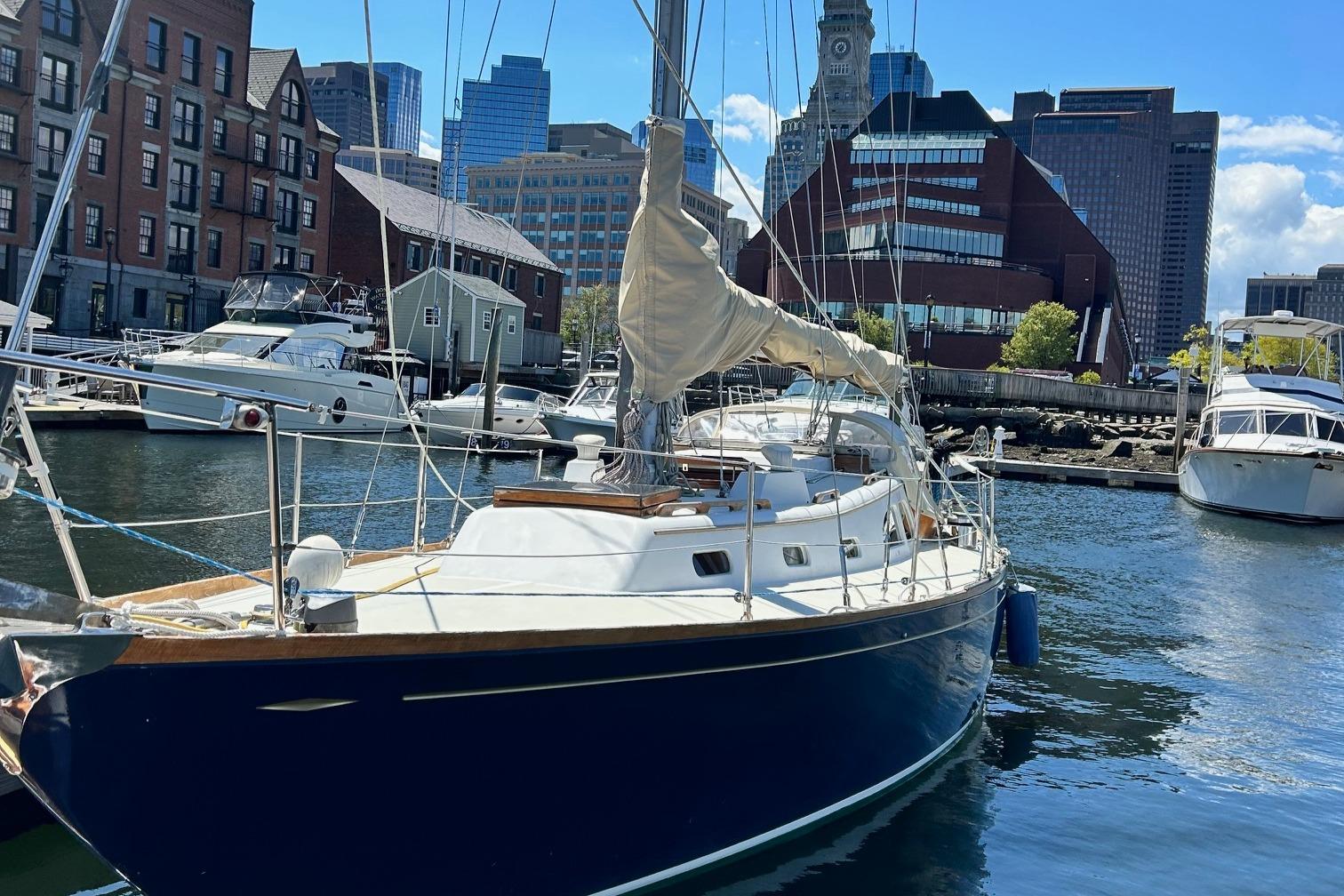 Sailboat LeComte Northeast 38, 1967, docked in urban marina with city skyline.