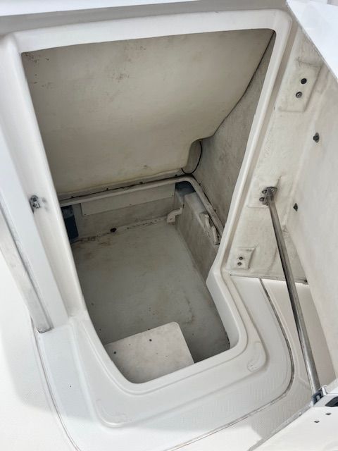 An open storage compartment on a boat with white walls and a hydraulic arm.