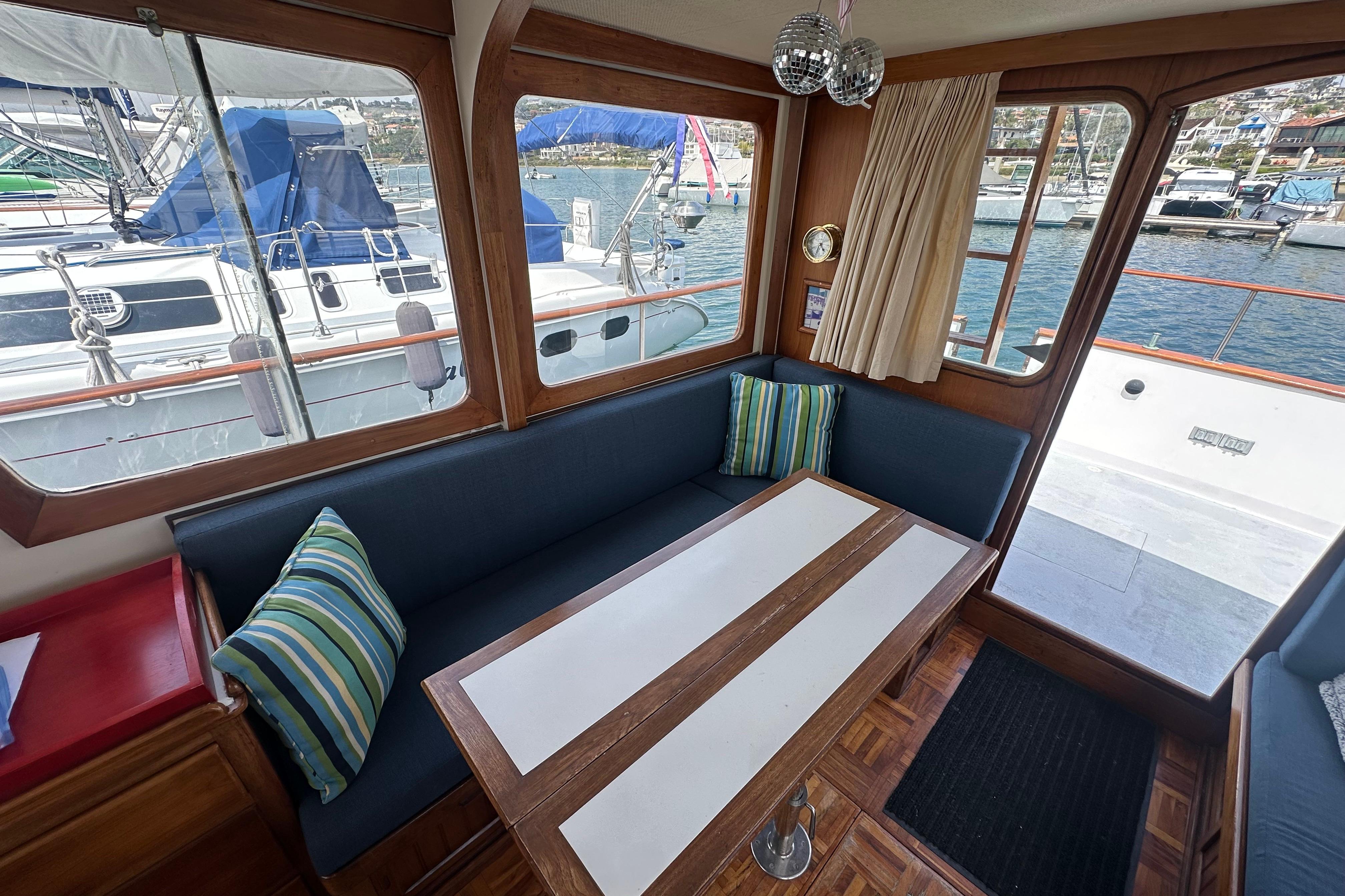 Interior of a 1973 CHB 33 boat with seating, table, and marina view.
