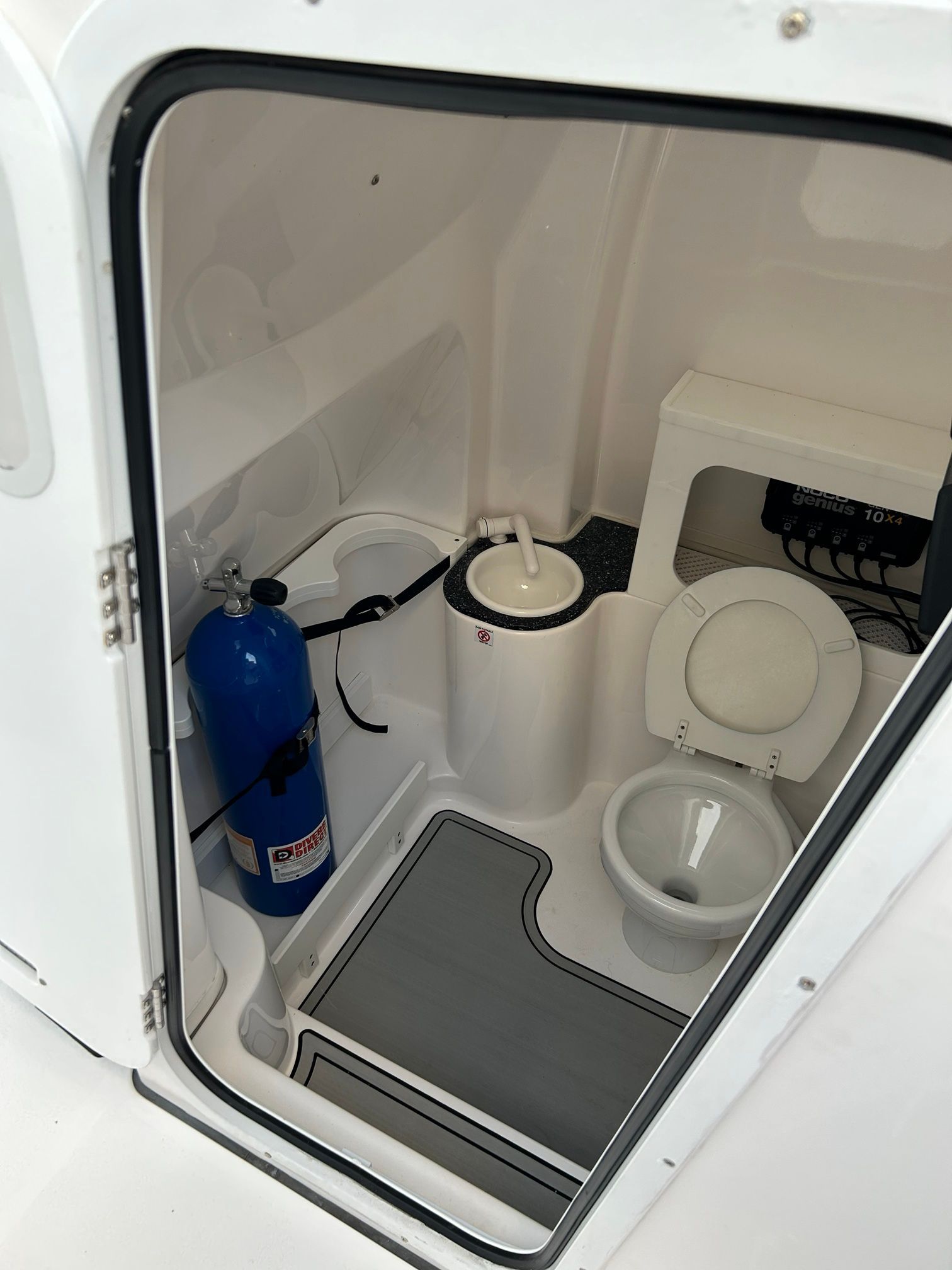 Interior of a boat cabin with a toilet and fire extinguisher.