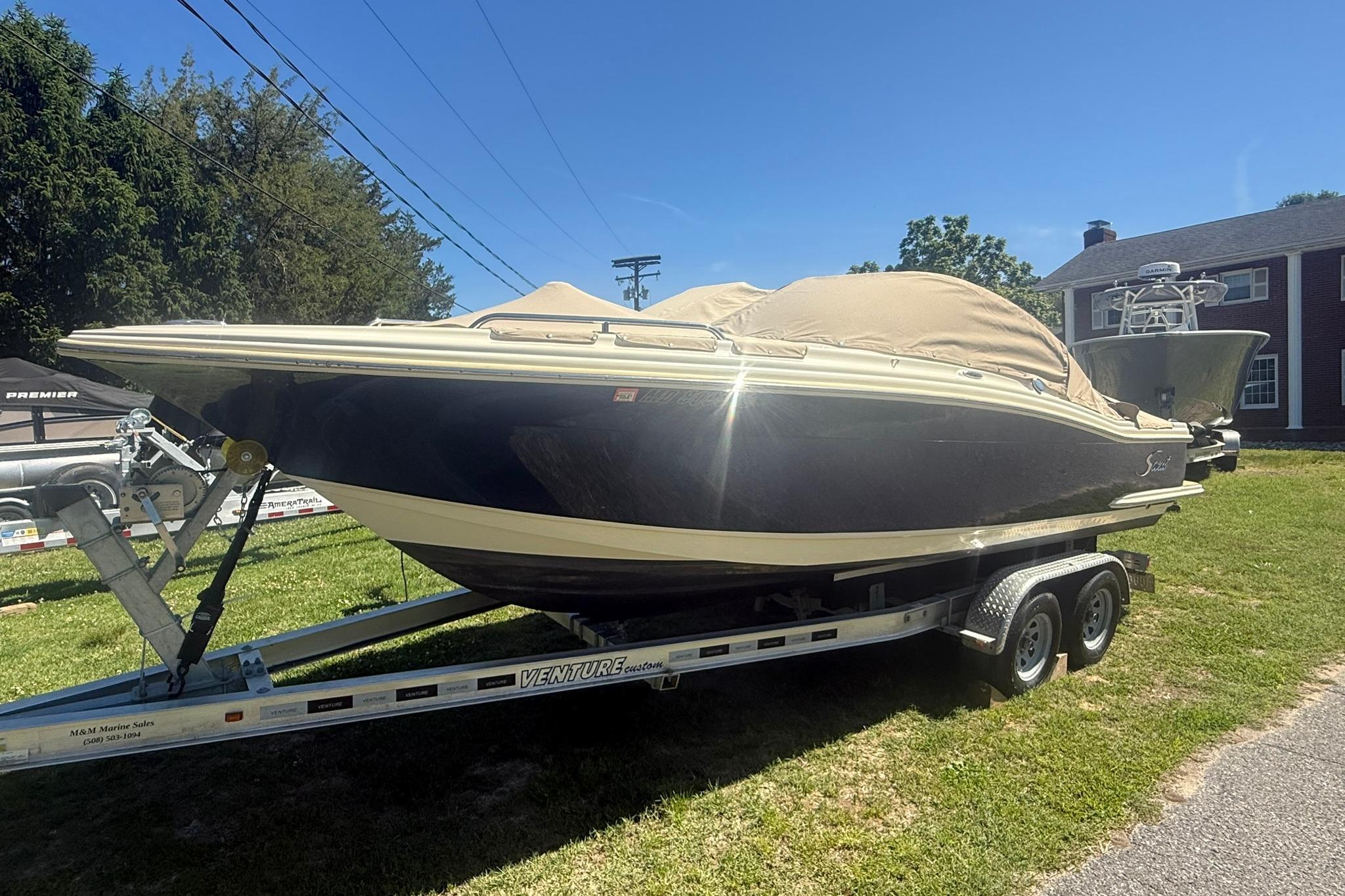 2021 Scout 215 Dorado boat on trailer, covered, parked on grass.