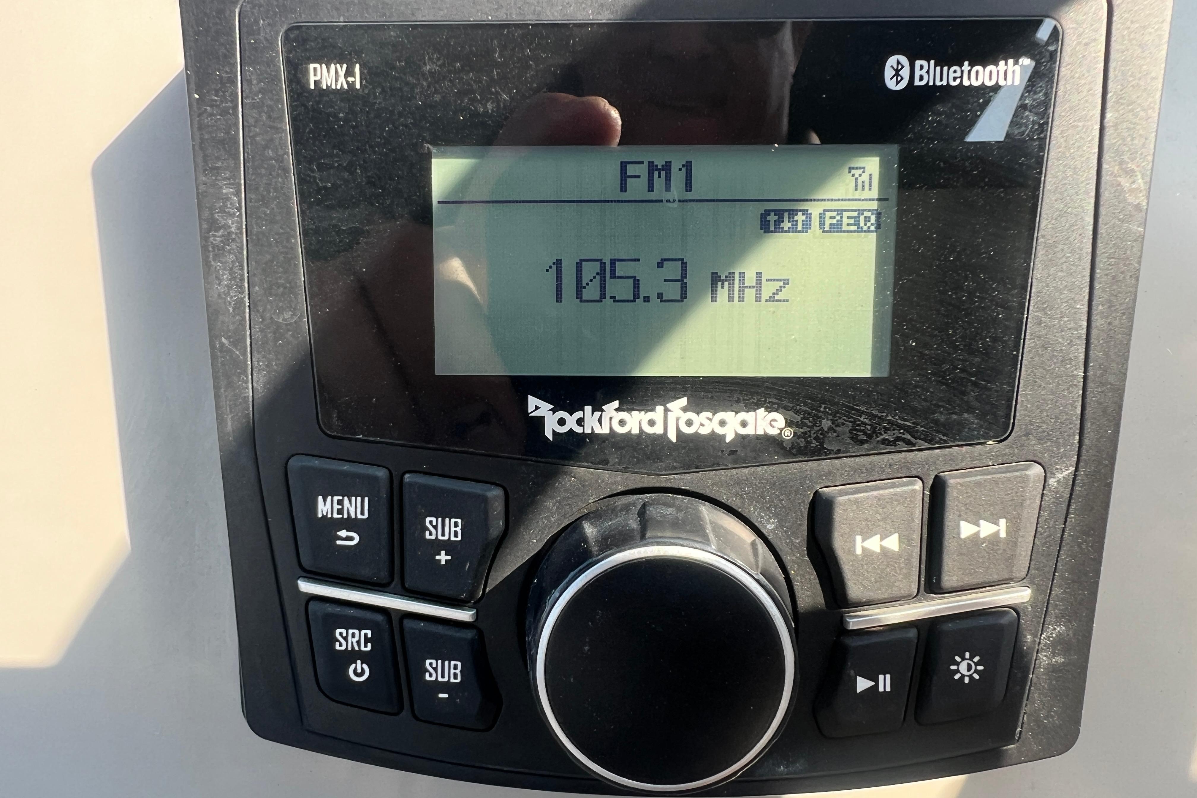 Rockford Fosgate PMX-1 stereo displaying FM radio at 105.3 MHz, Bluetooth enabled.