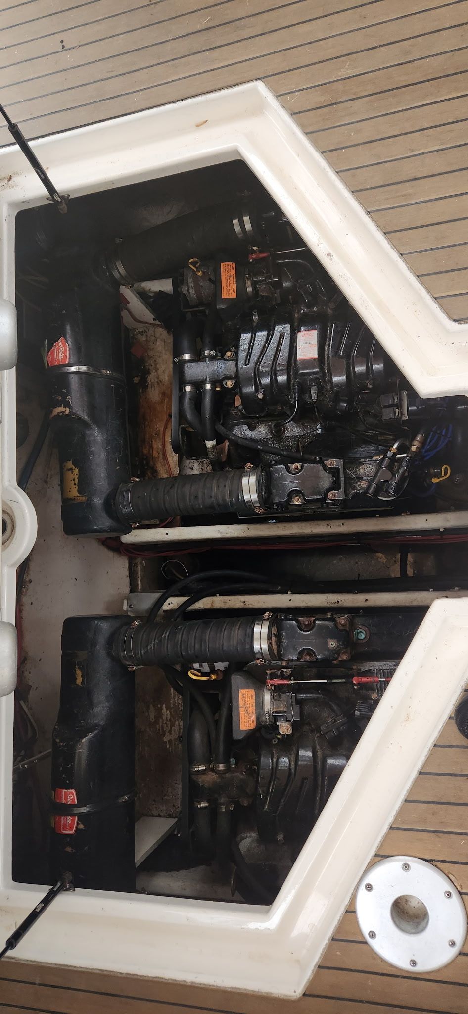 Two engines in a boat's engine compartment, surrounded by wooden paneling.