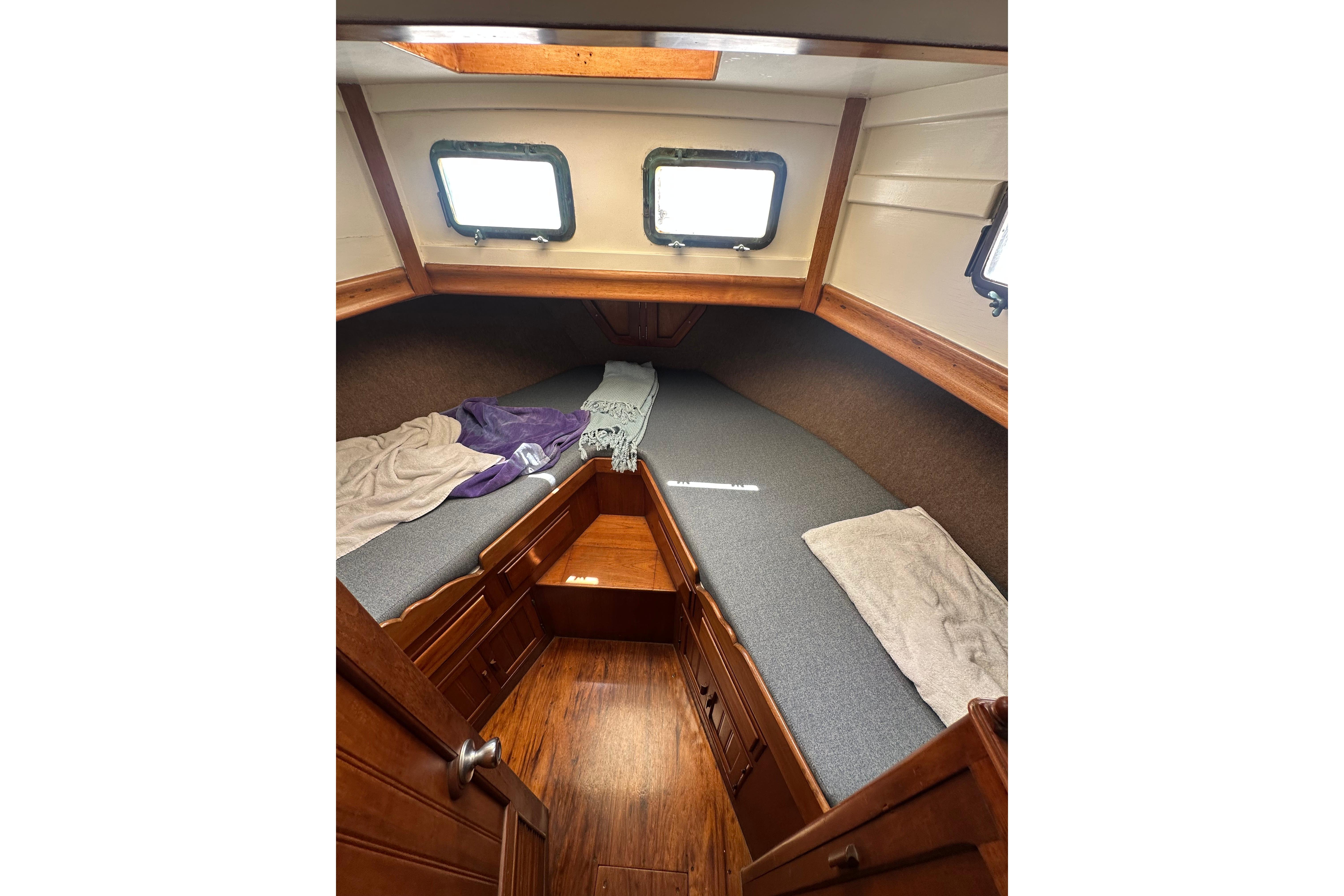 Cozy cabin interior of a 1973 CHB 33 boat with wooden accents and twin windows.