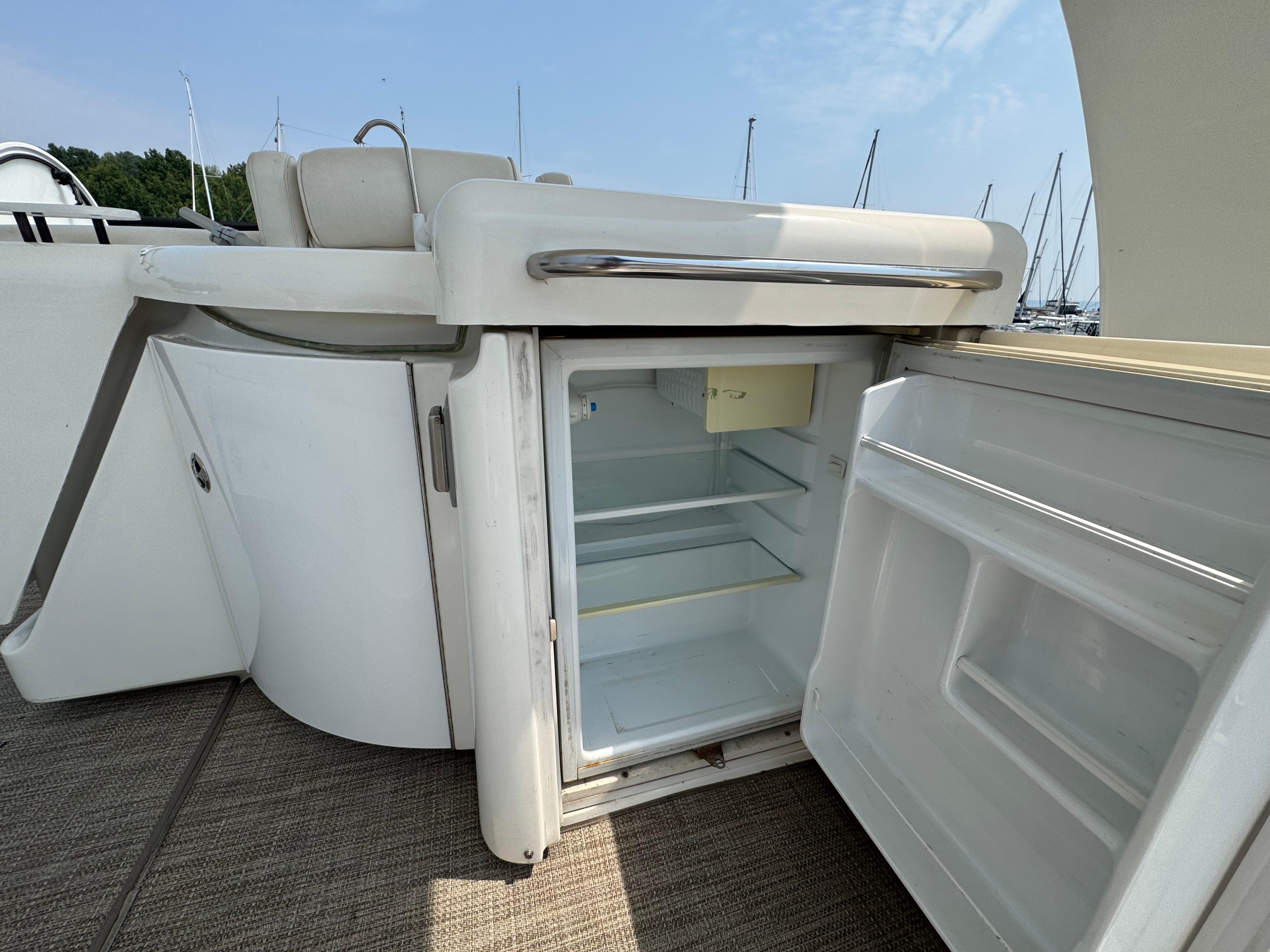Open fridge on 2003 Cruisers Yachts 5000 Sedan Sport, showcasing interior storage space.