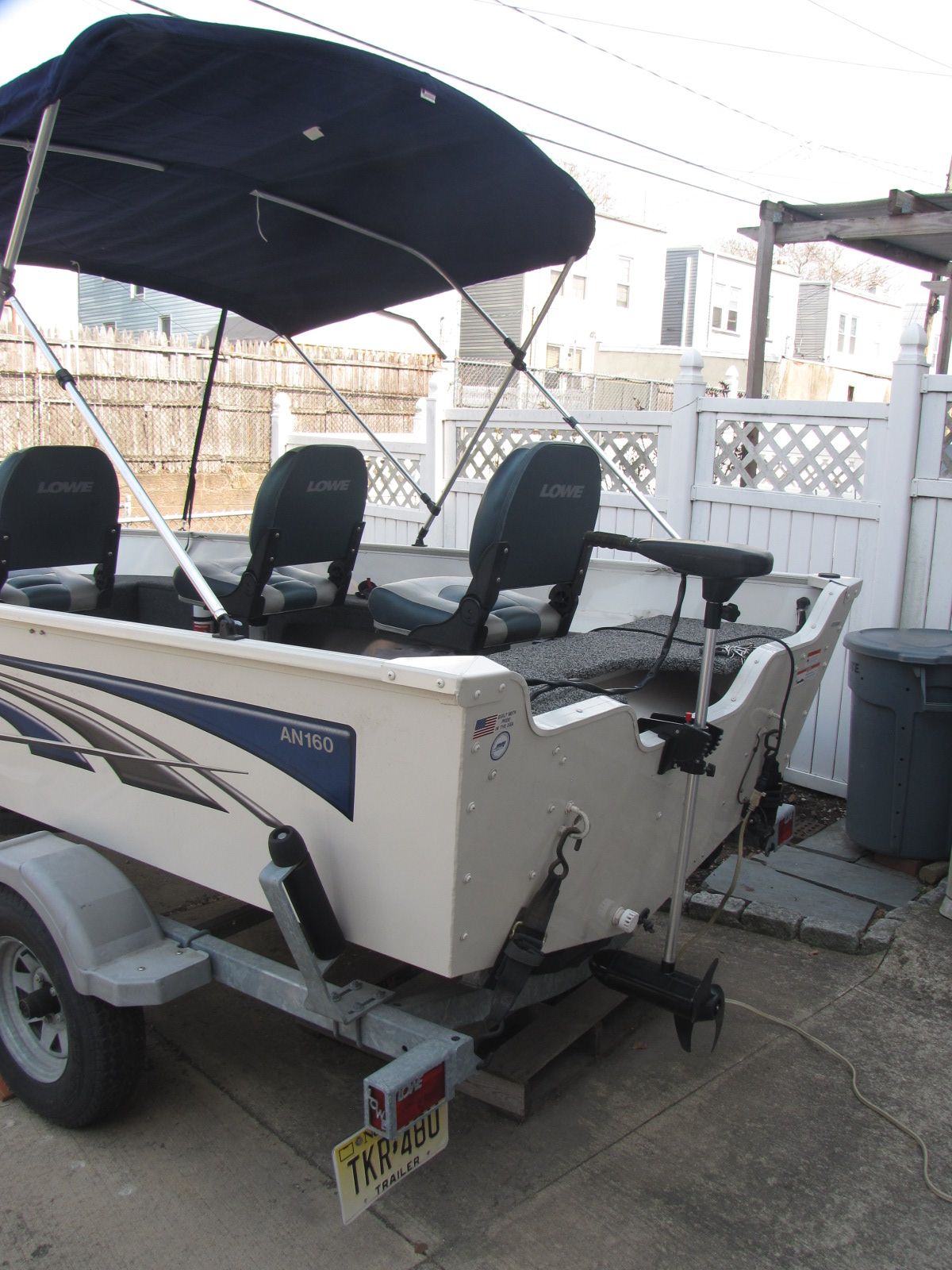 A Lowe Angler 160T boat on a trailer in a yard.