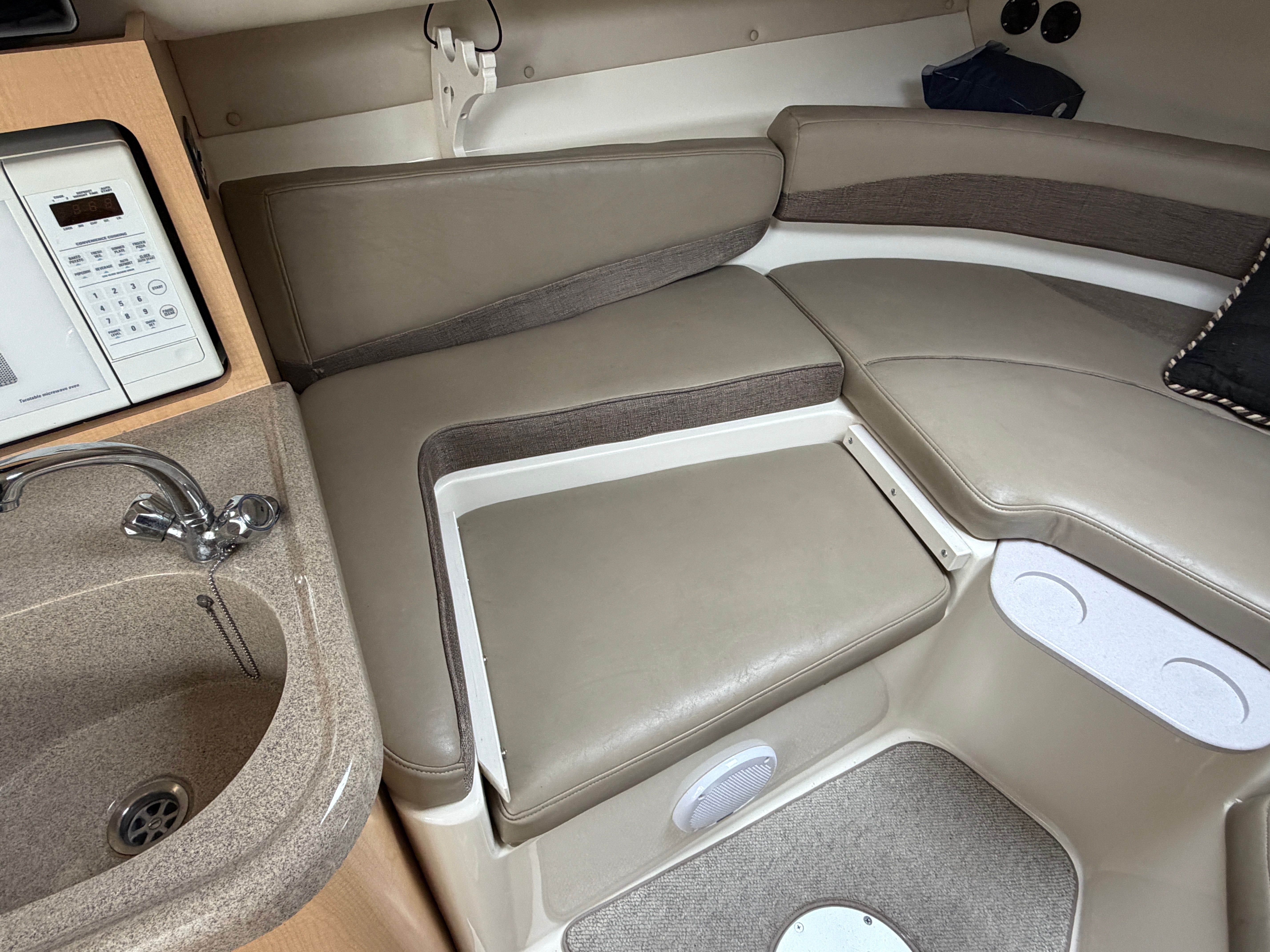 Interior of a 2001 Boston Whaler 26 Conquest with cushioned seating and a small sink.