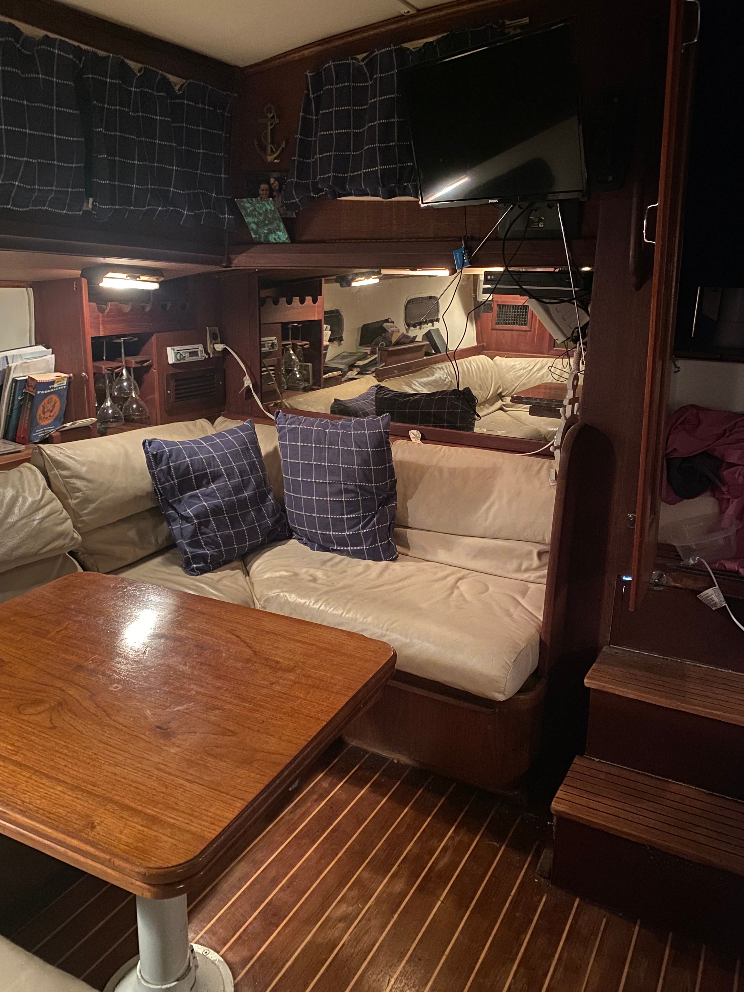 Interior of a 1983 Islander Freeport with cozy seating, wooden table, and nautical decor.