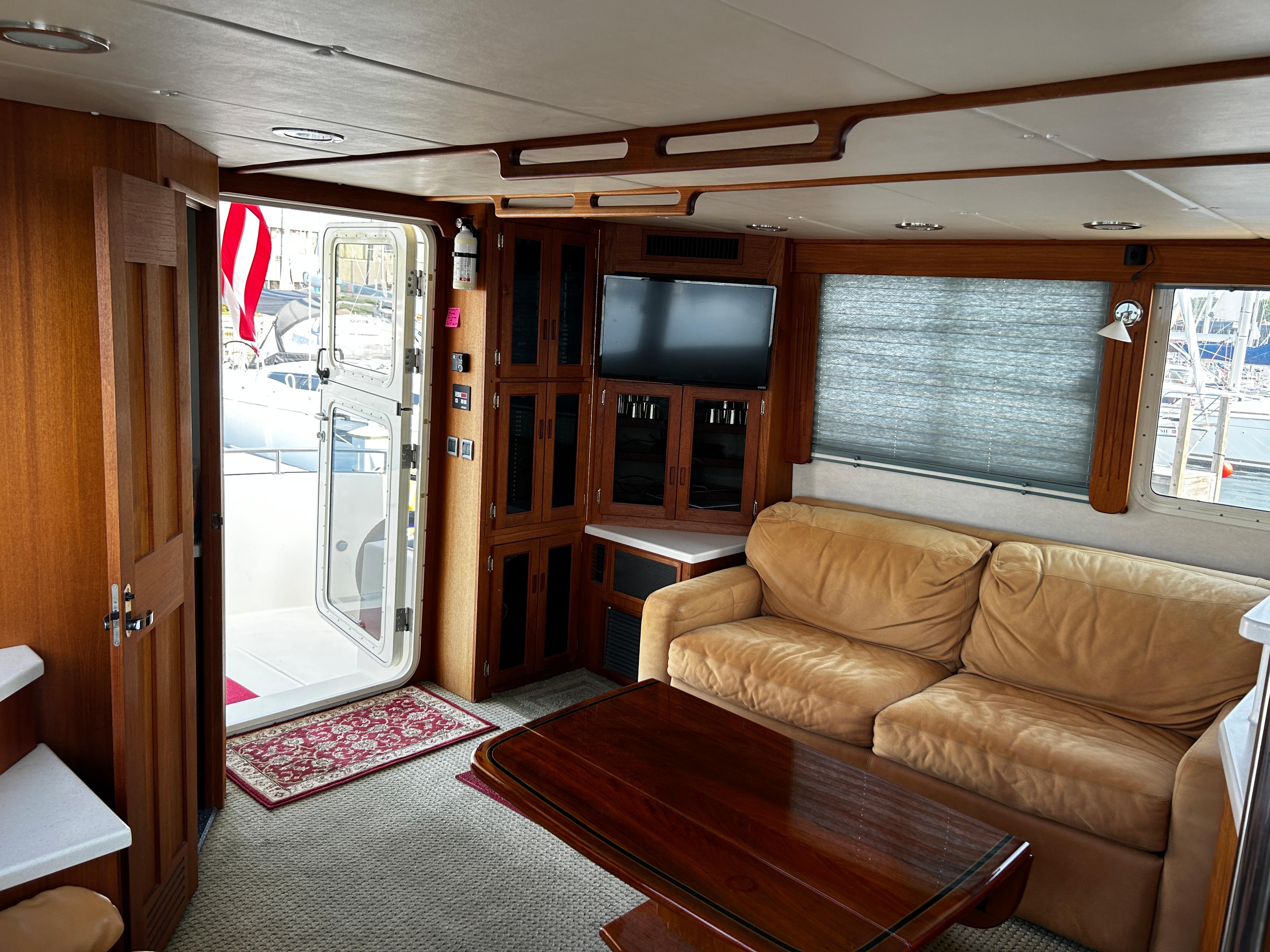 2003 Nordic Tug 52 interior with beige sofa, wooden table, and TV.
