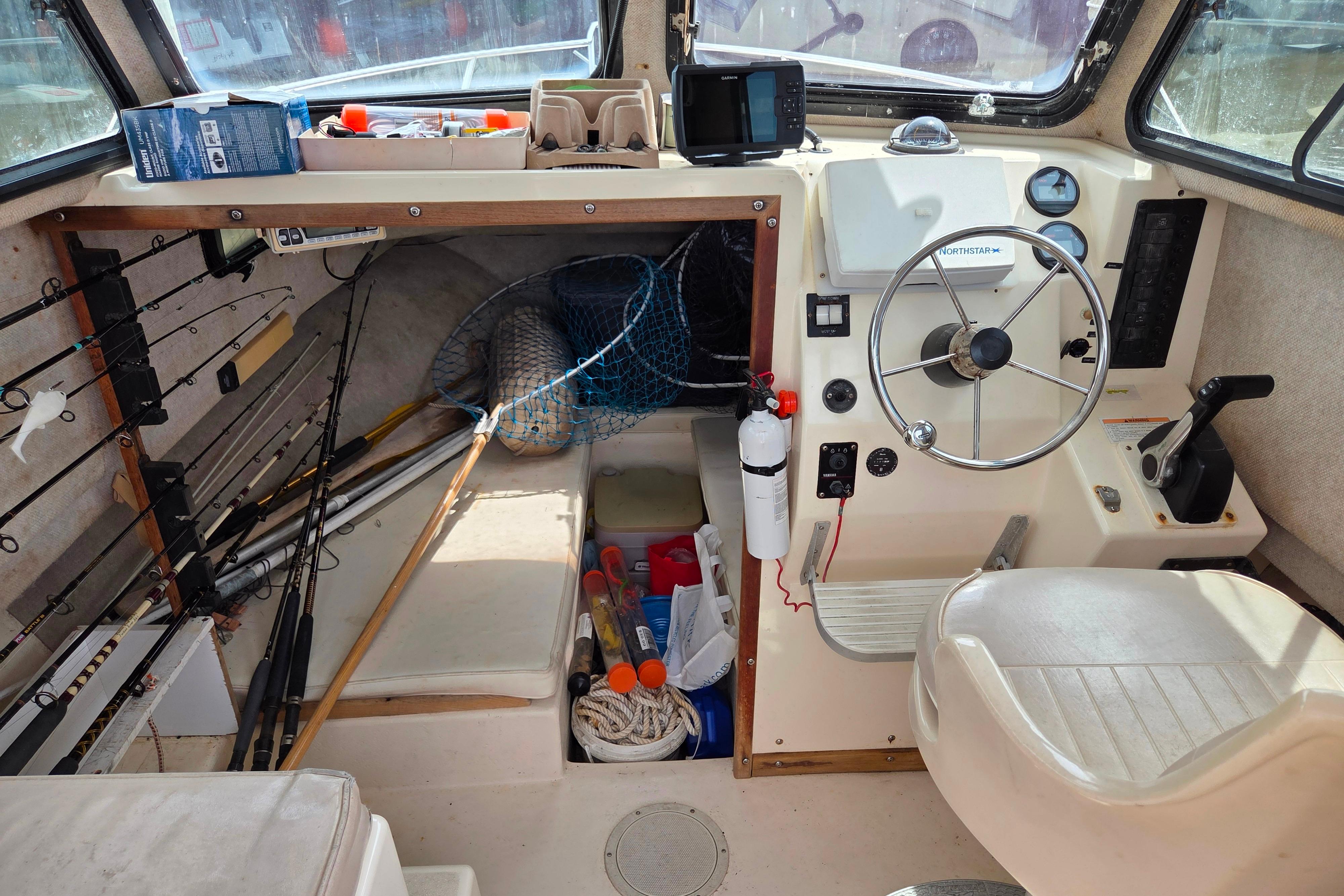 Interior of a 2002 Parker 2520 Deep Vee Sport Cabin with fishing gear and steering controls.