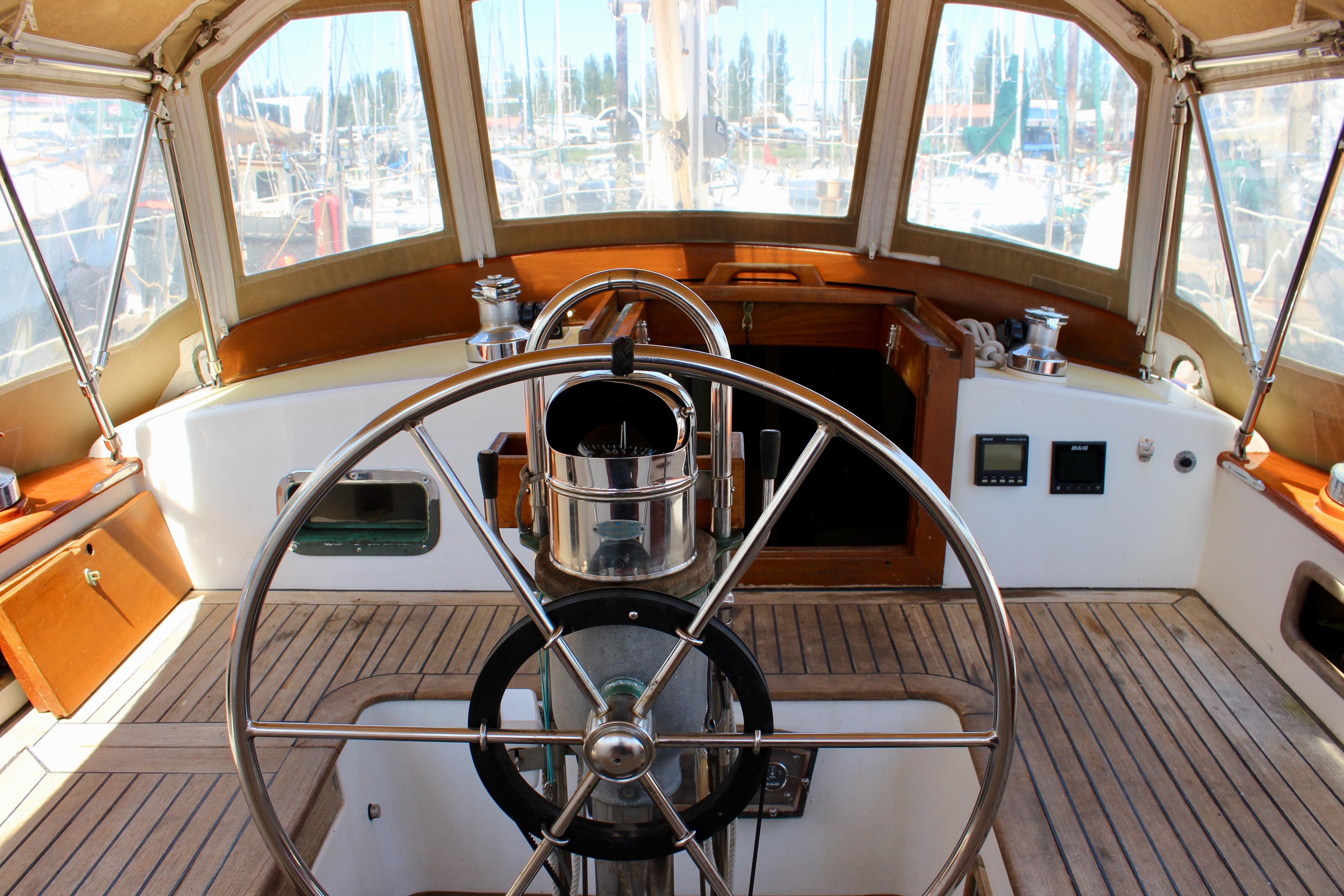 Cockpit of a 1981 Kelly Peterson 46 sailboat with wooden and metal steering wheel.