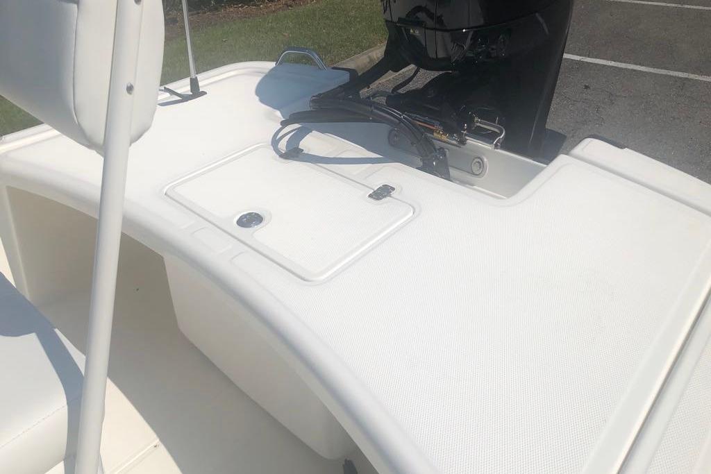 2026 Mako Pro Skiff 17 CC boat deck with outboard motor in parking lot.
