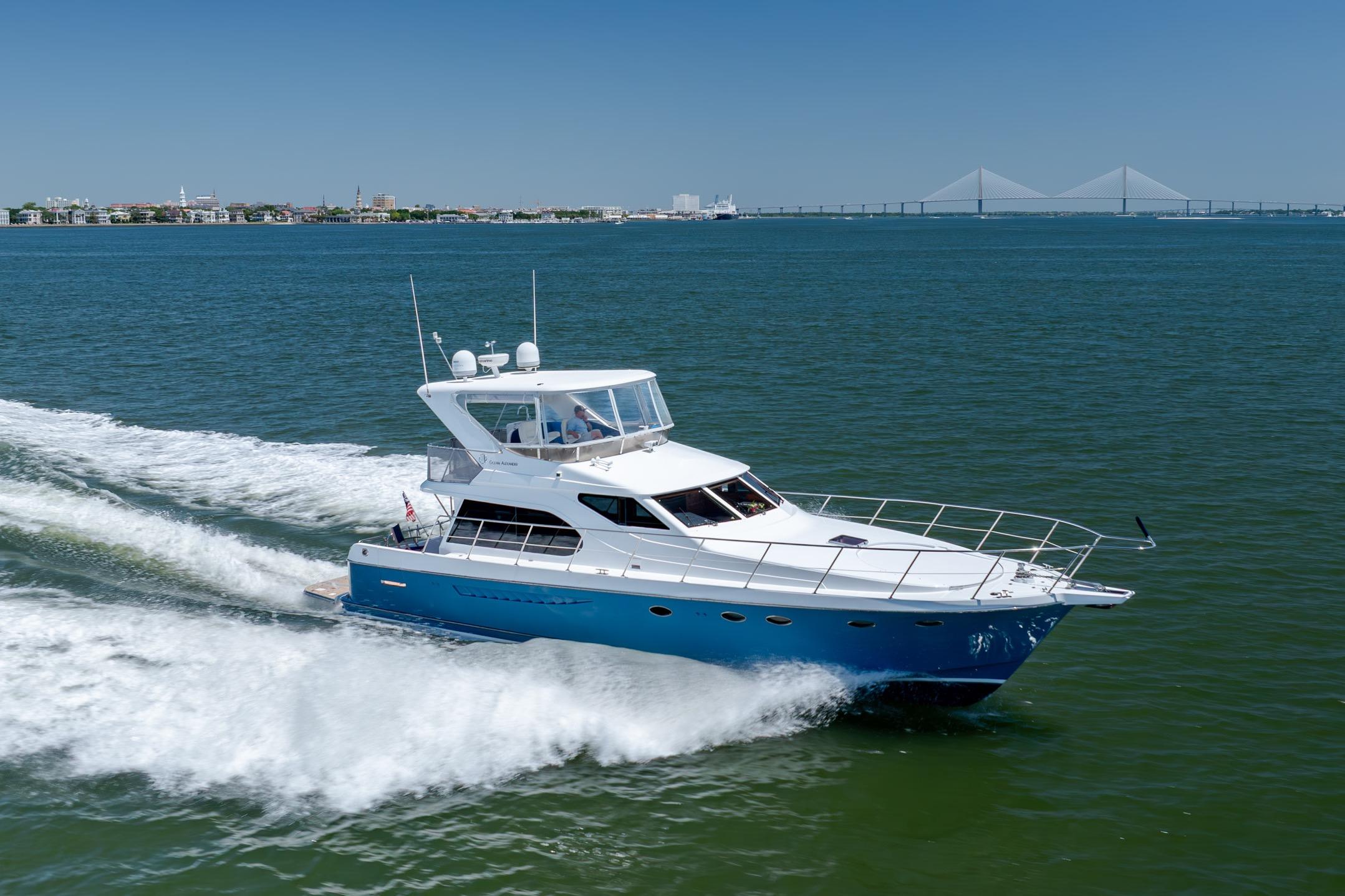 Ocean Alexander yacht cruising on open water with cityscape and bridge in background.
