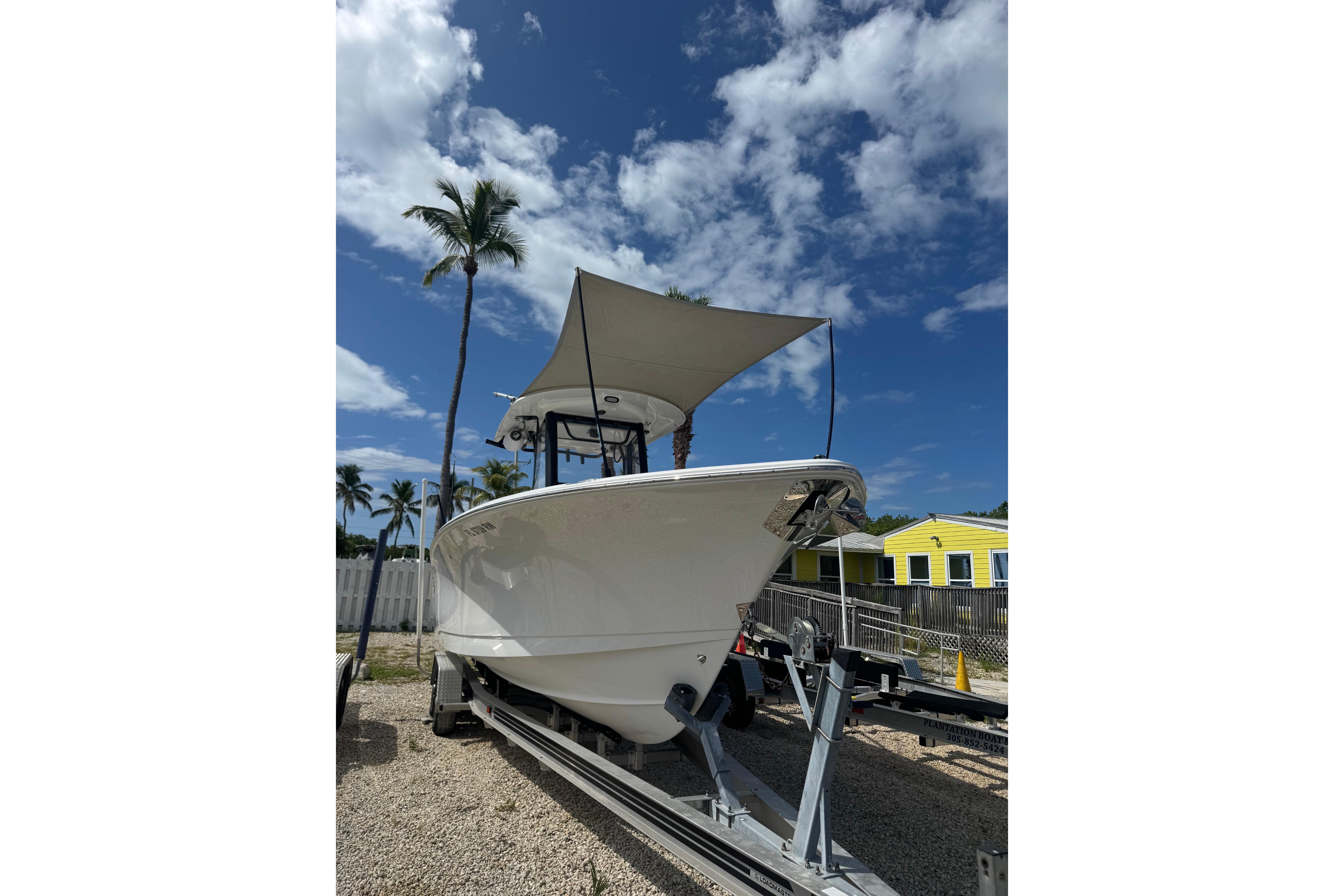 2019 Sea Hunt Gamefish 27 Coffin Box boat on trailer under blue sky with palm trees.
