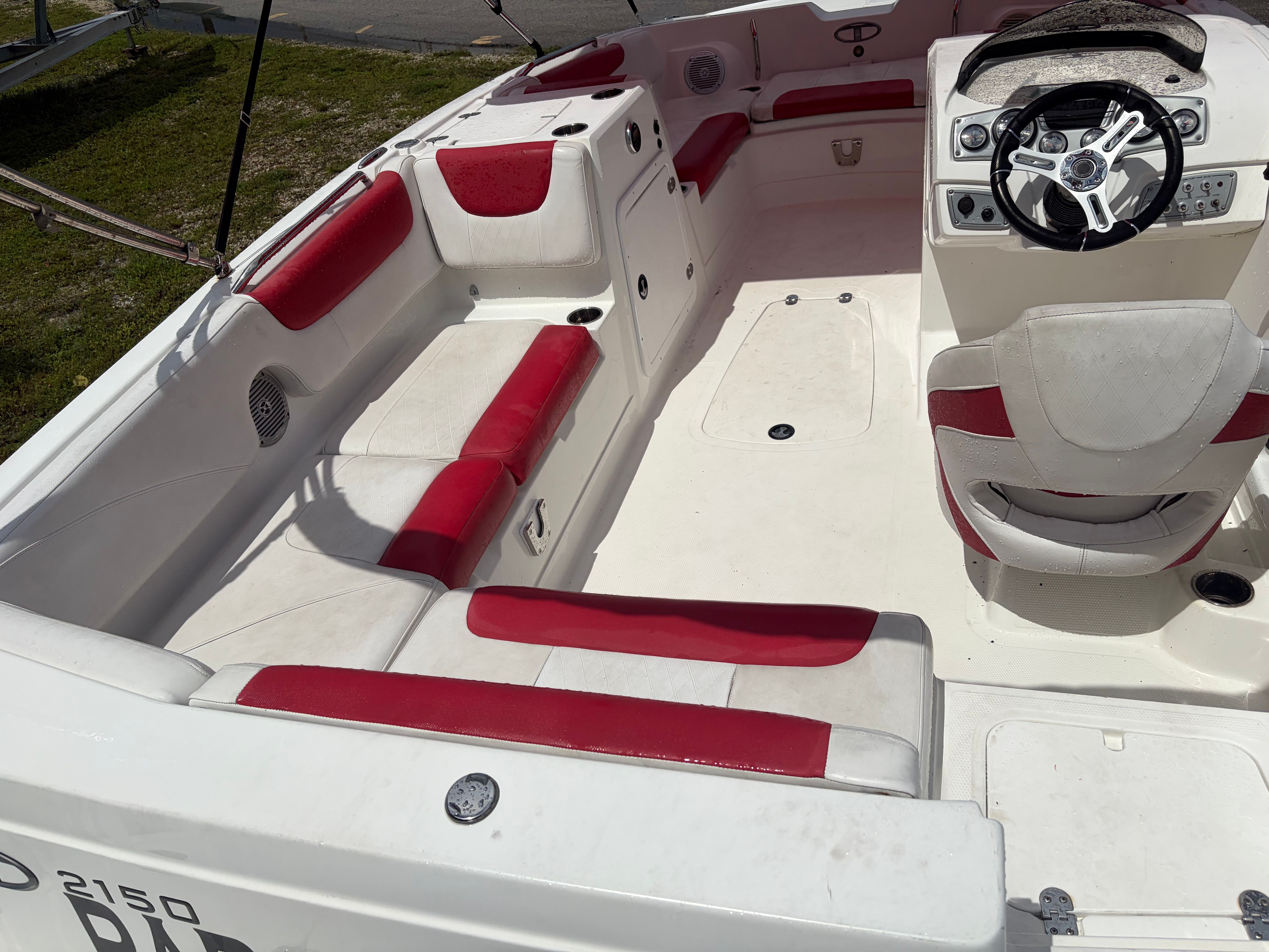 The image shows the cockpit of a 2019 Tahoe 21.5 boat with red and white seating.