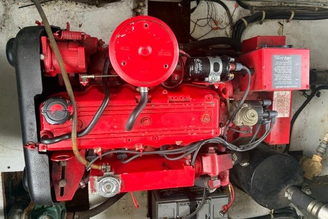 Red engine of a 1997 Stardust Houseboat 18x83, showcasing mechanical components and wiring.