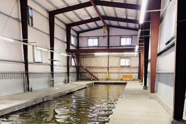 Spacious 1985 Custom Larson Boathouse interior with water channel and metal structure.