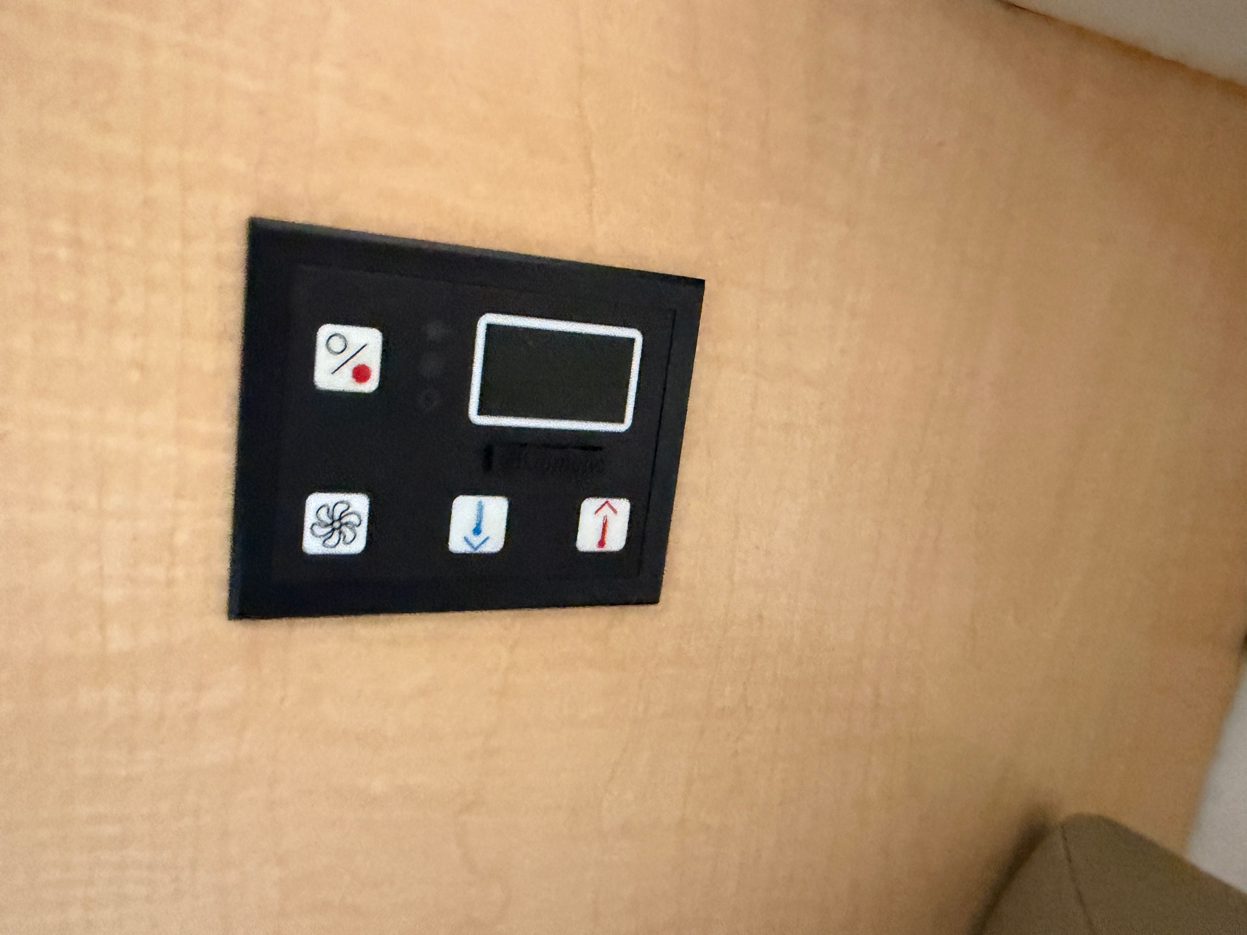 A control panel with fan and temperature regulation symbols on a wooden panel.