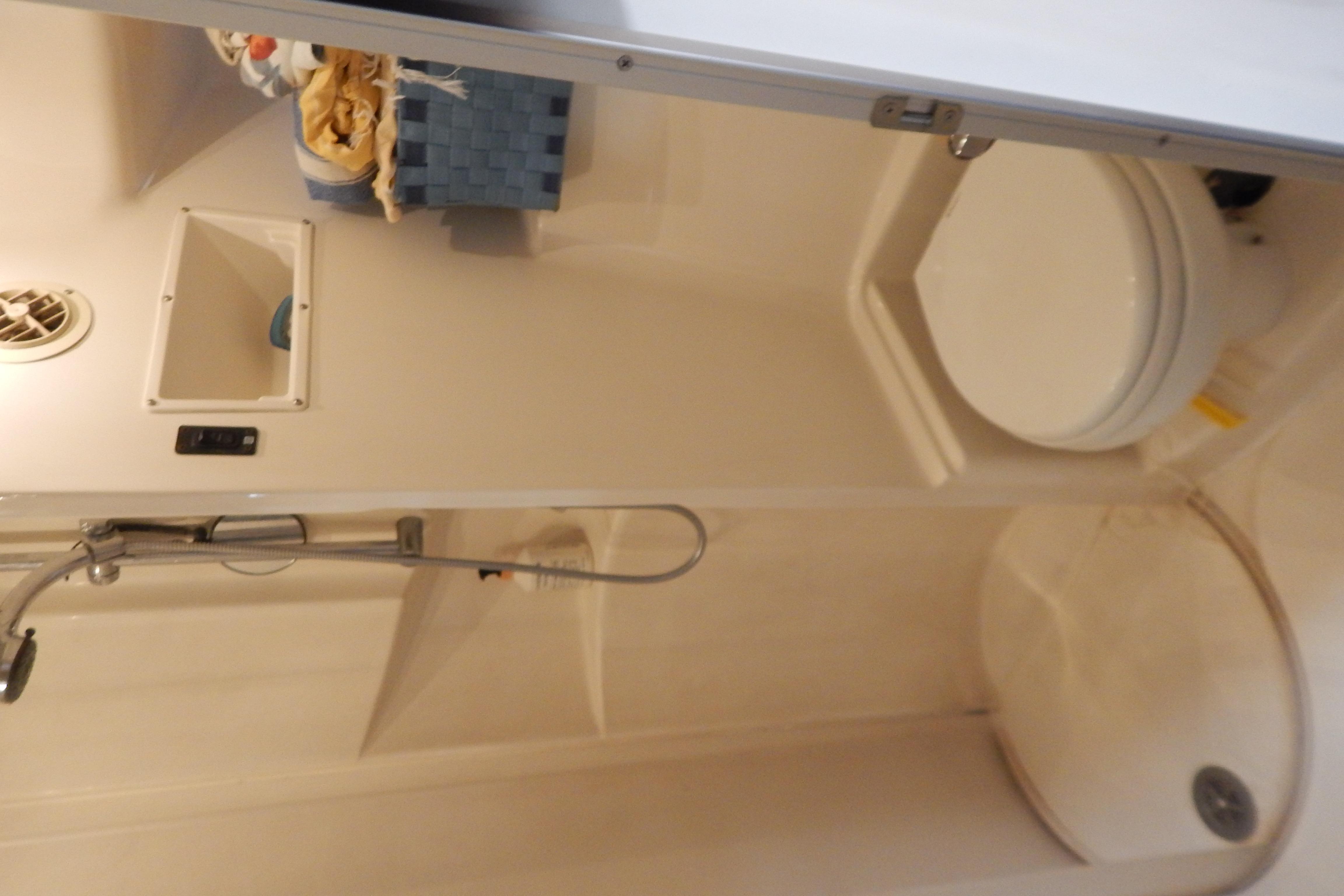 Compact bathroom in a 1998 Magnum 4100 SCR, featuring a shower and toilet.