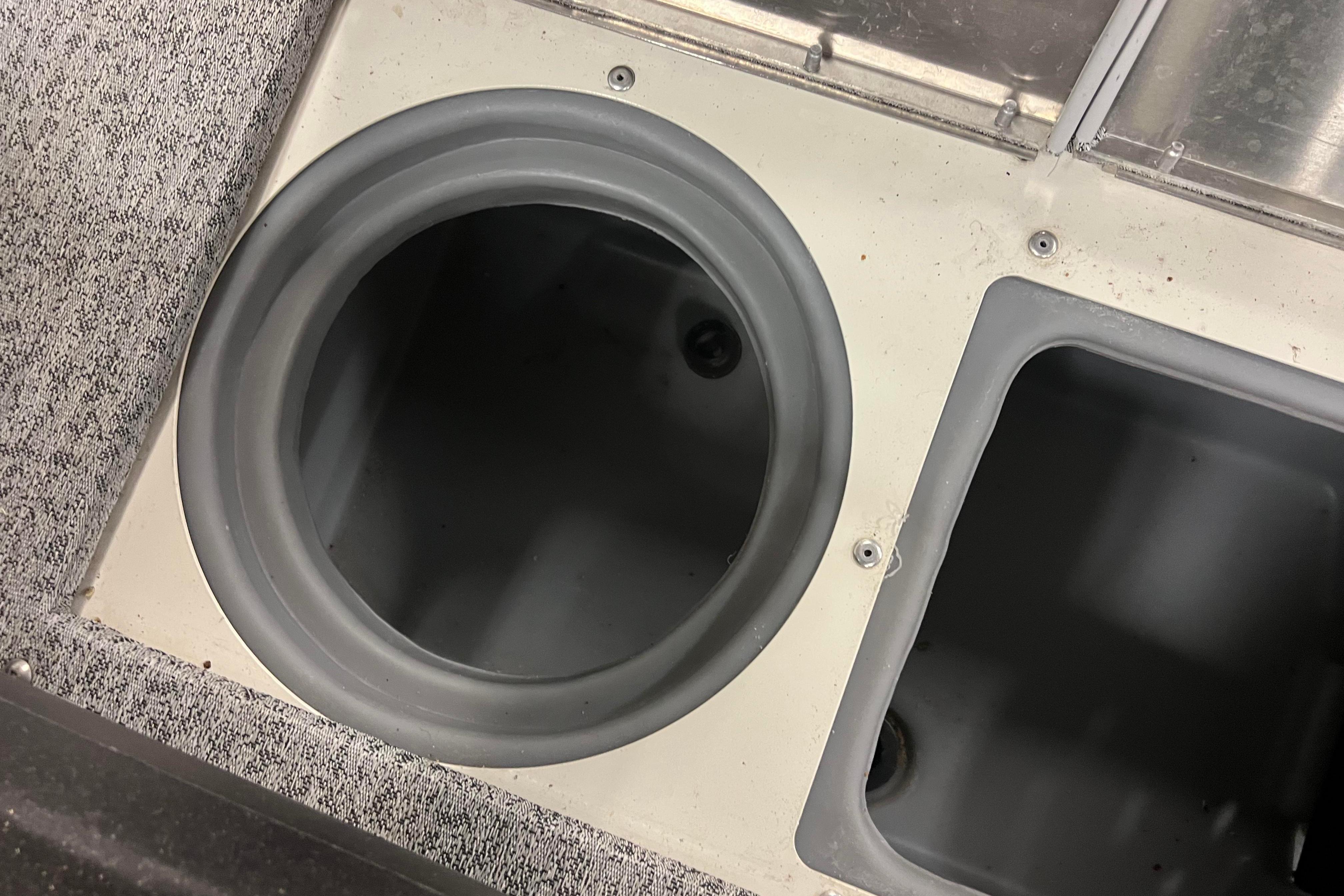 2022 Tracker Pro Guide V-16 WT boat storage compartments, circular and rectangular, with carpeted surface.
