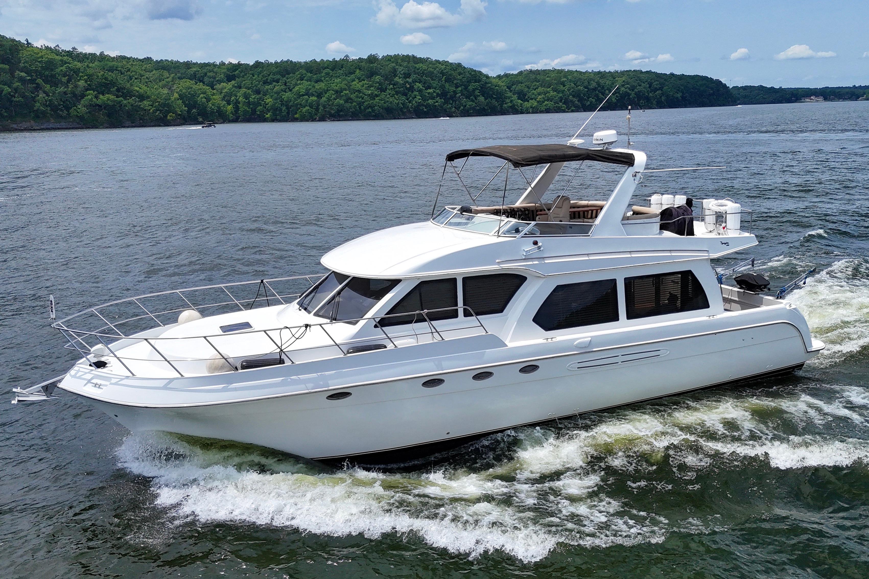 2007 Navigator 5100 yacht cruising on a scenic lake with lush green shoreline.