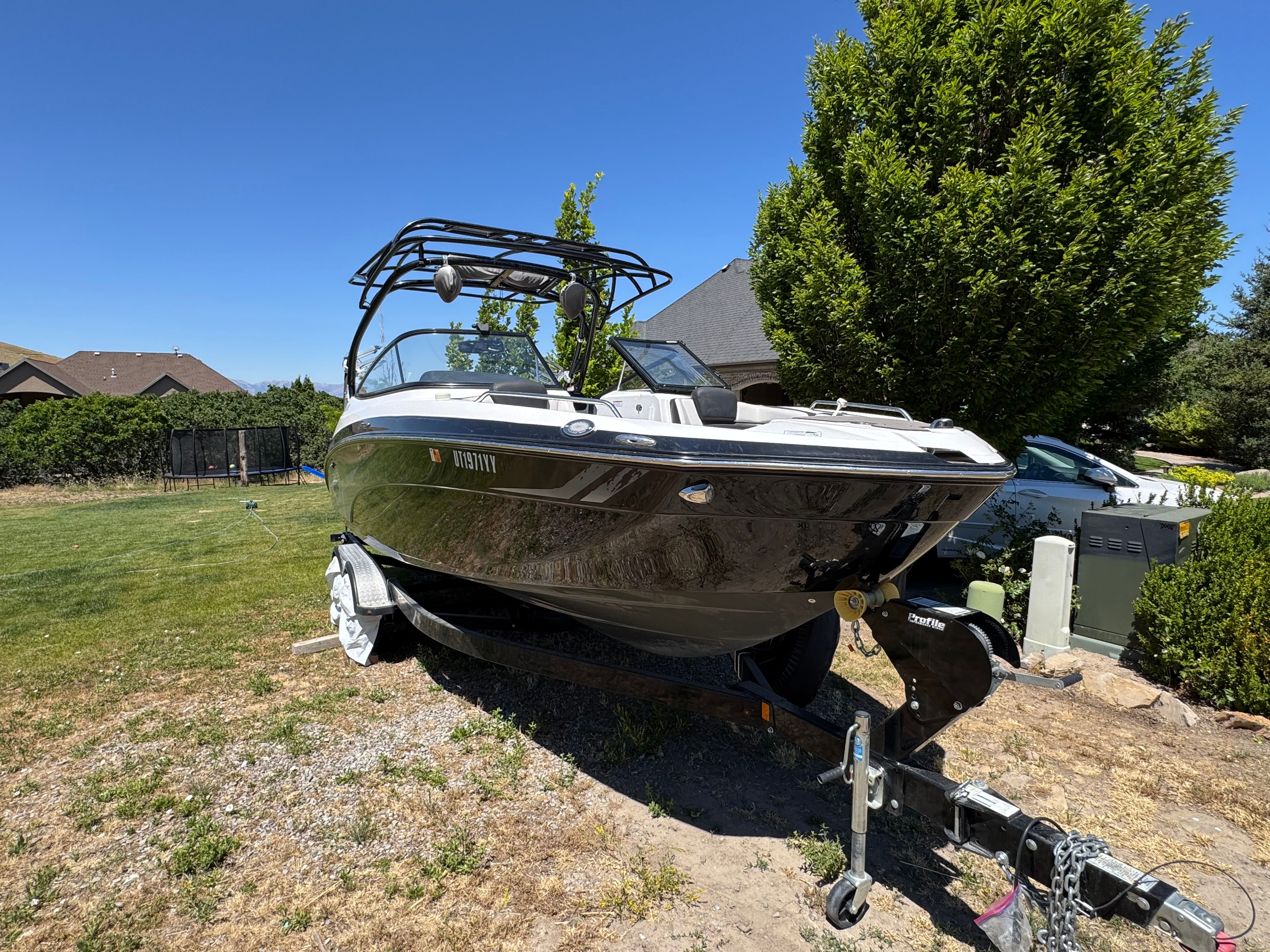 A 2017 Yamaha 242X E-Series boat on a trailer in a yard.