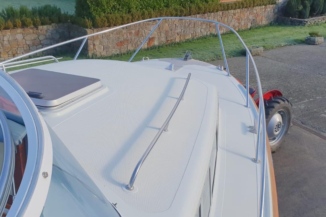 1989 Fairey Spearfish MKIII boat deck with railing, parked near stone wall and greenery.