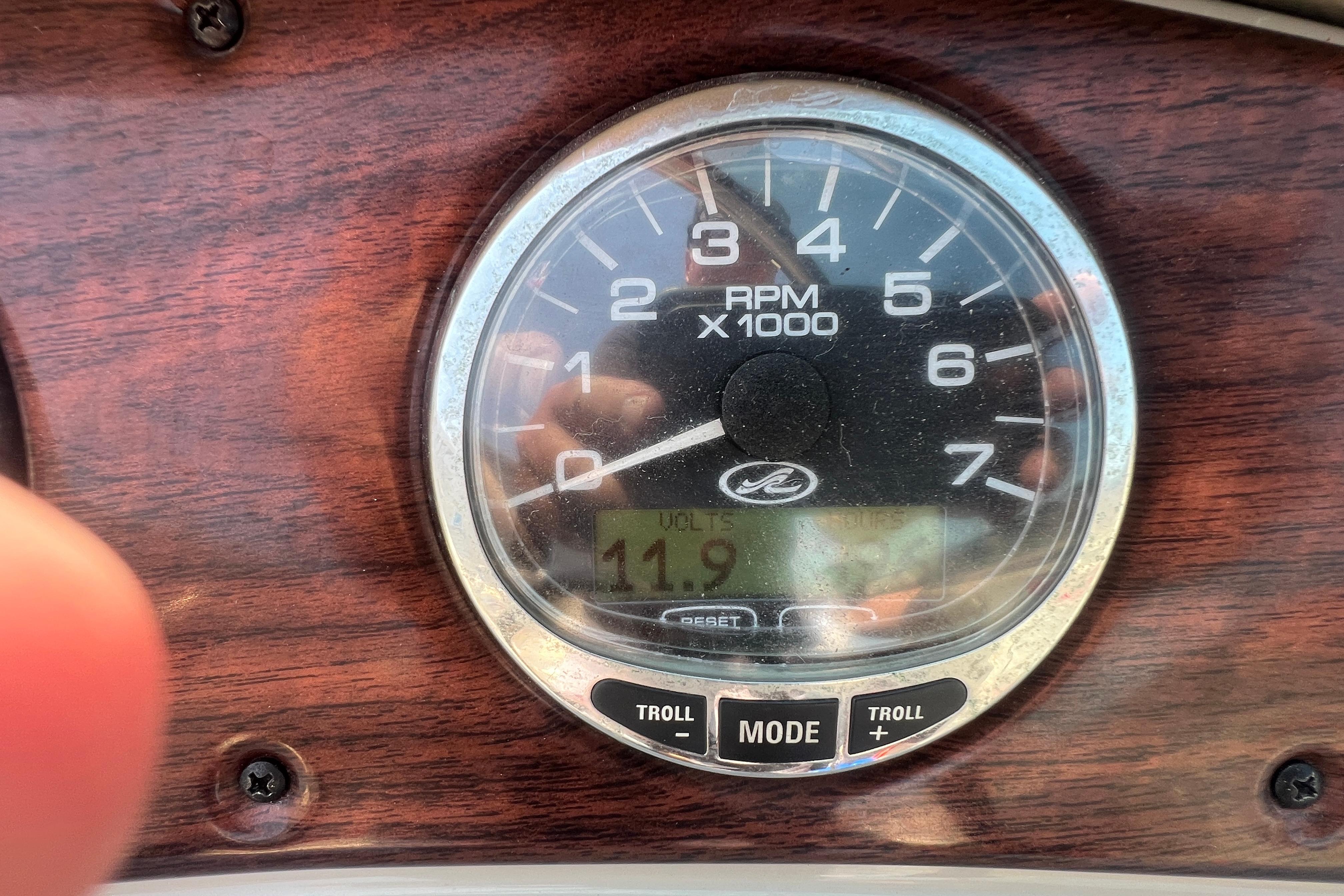 Close-up of 2005 Sea Ray 240 Sundeck RPM gauge on wooden dashboard.