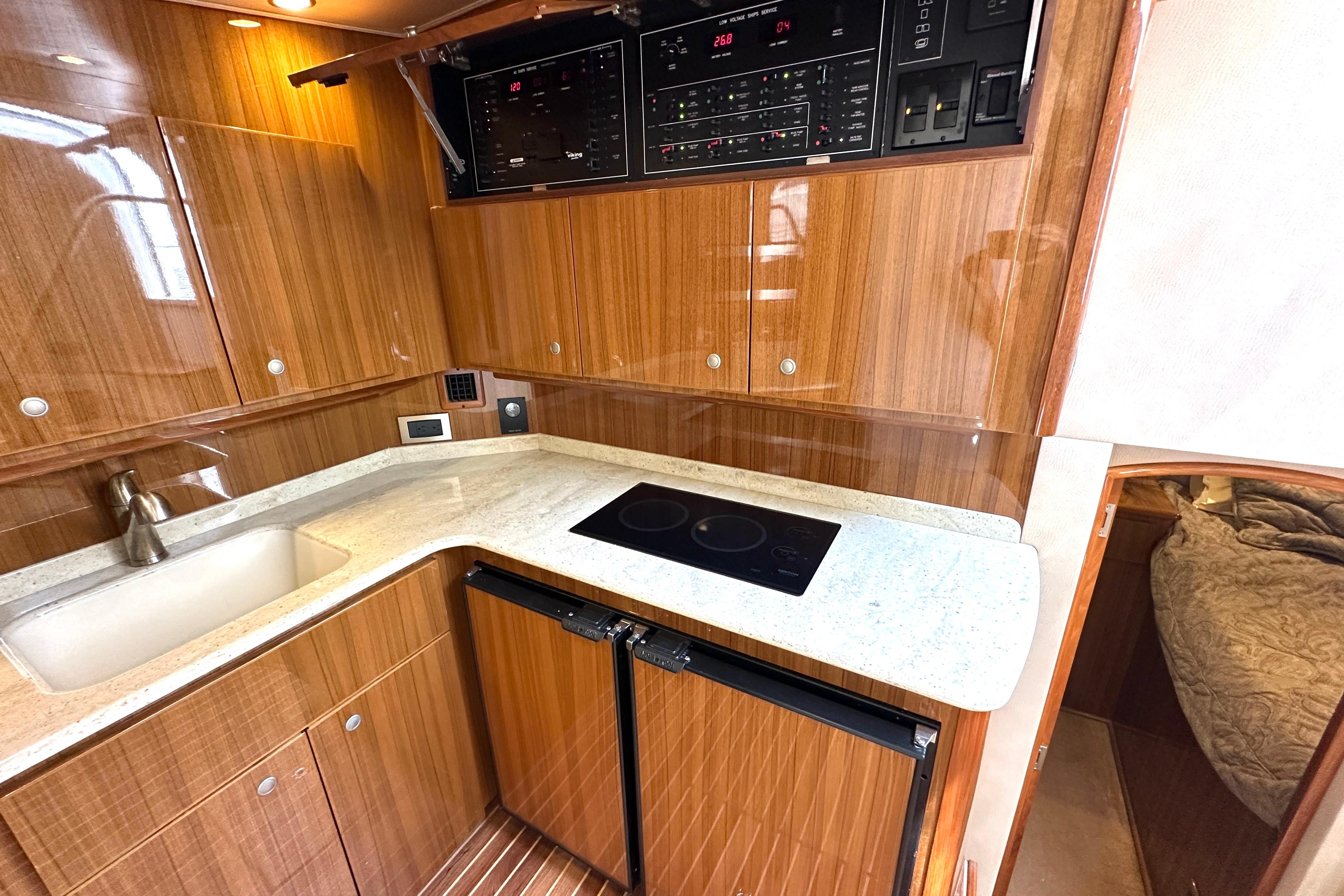 Luxurious 2012 Viking 42 Open yacht kitchen with wood cabinetry and modern appliances.