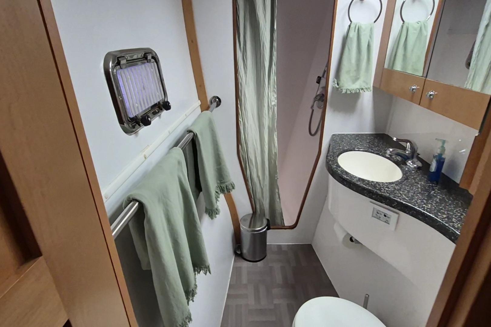 Bathroom interior of 2009 Endeavour 40 Skylounge yacht with sink, shower, and towels.