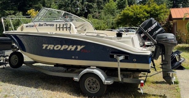 A 2007 Bayliner Trophy Pro 1902 boat on a trailer, surrounded by trees.