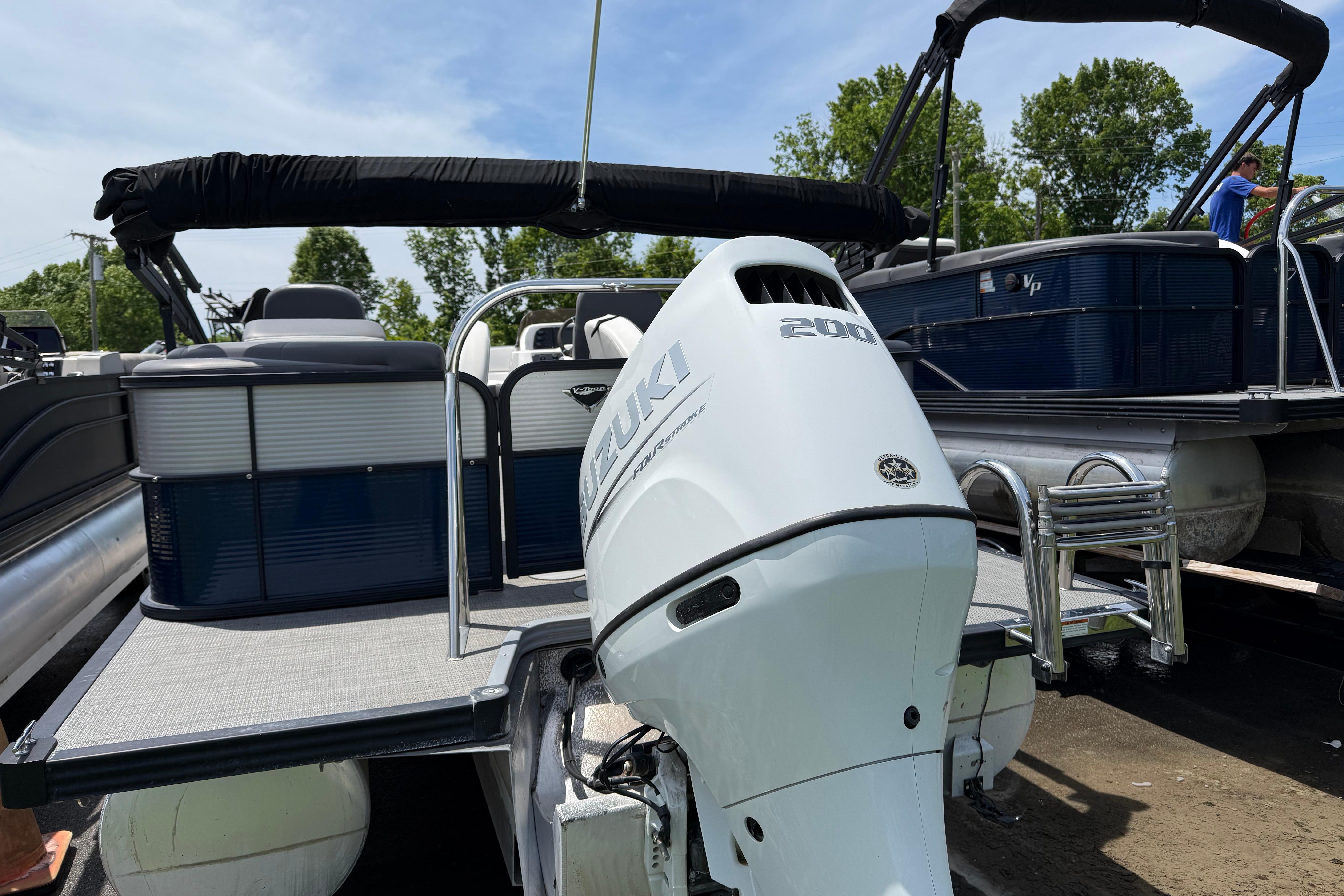 2022 Manitou Aurora LE pontoon boat with Suzuki 200 outboard motor, docked outdoors.