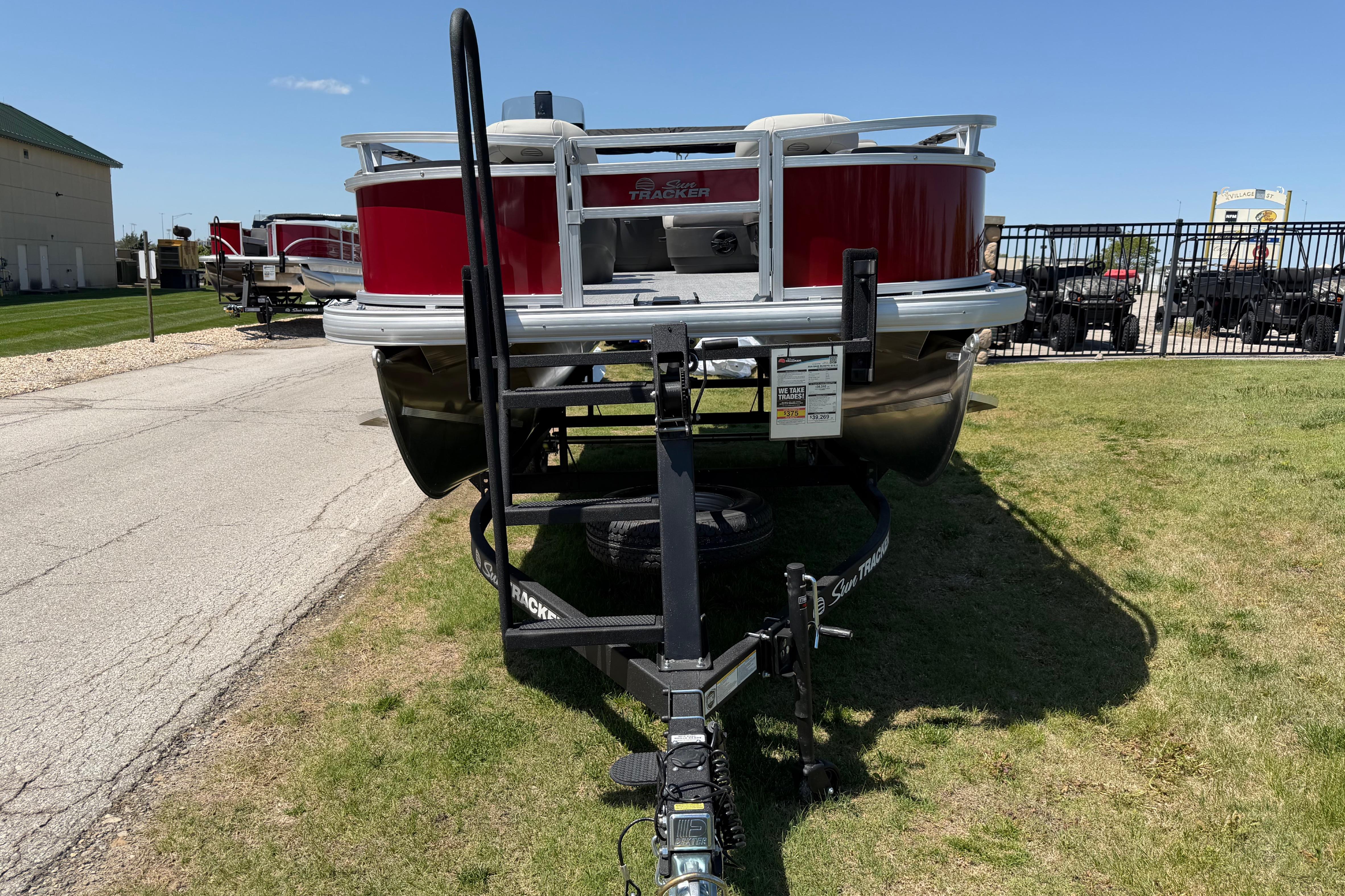 2026 Sun Tracker Bass Buggy 18 DLX pontoon boat on trailer, parked outdoors.